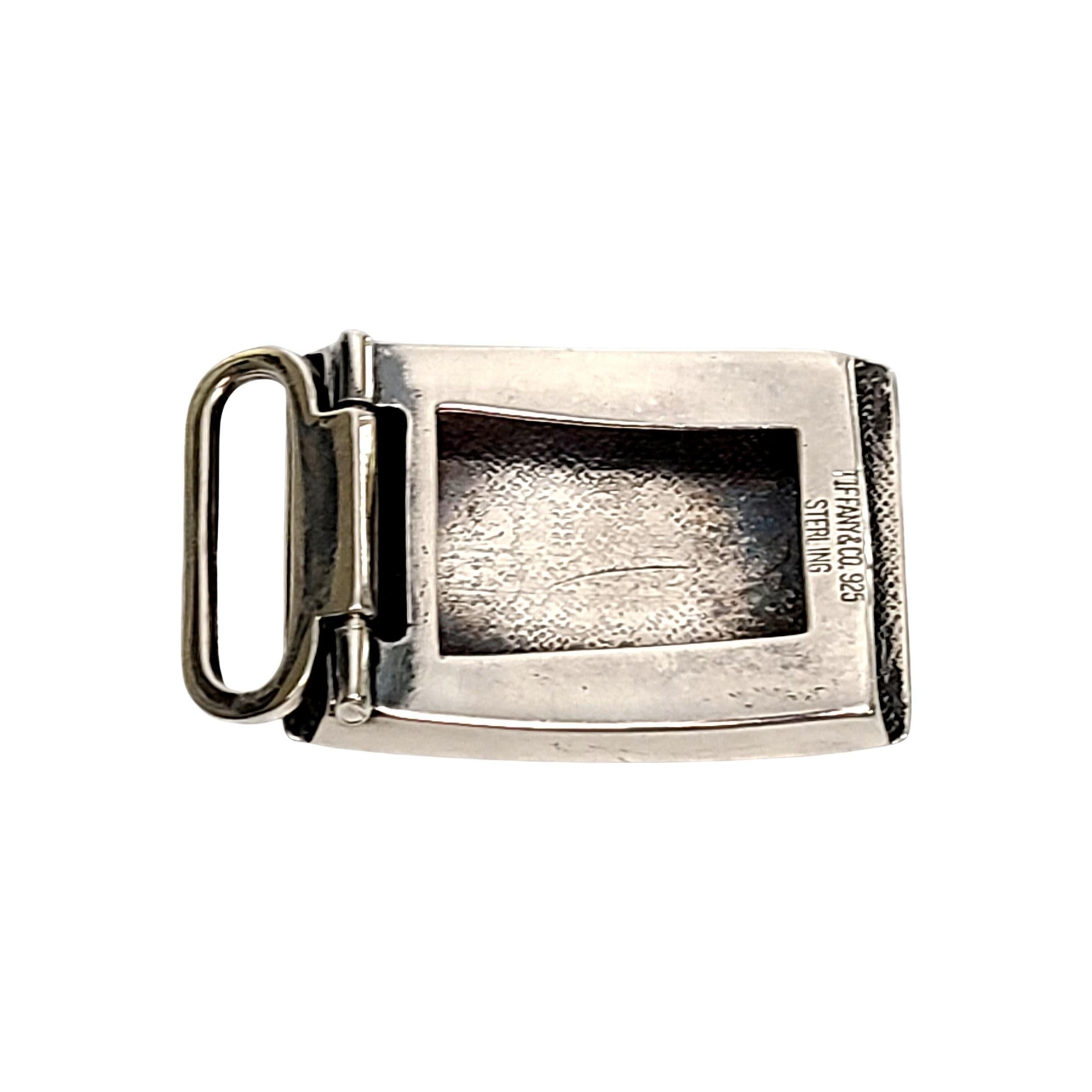 Sterling silver belt bucke by Tiffany & Co.

No monogram.

Rectangle shaped sterling silver belt buckle with etched stripe design framing the buckle. There had been a monogram at the center, which has been removed. As a result there is some waving