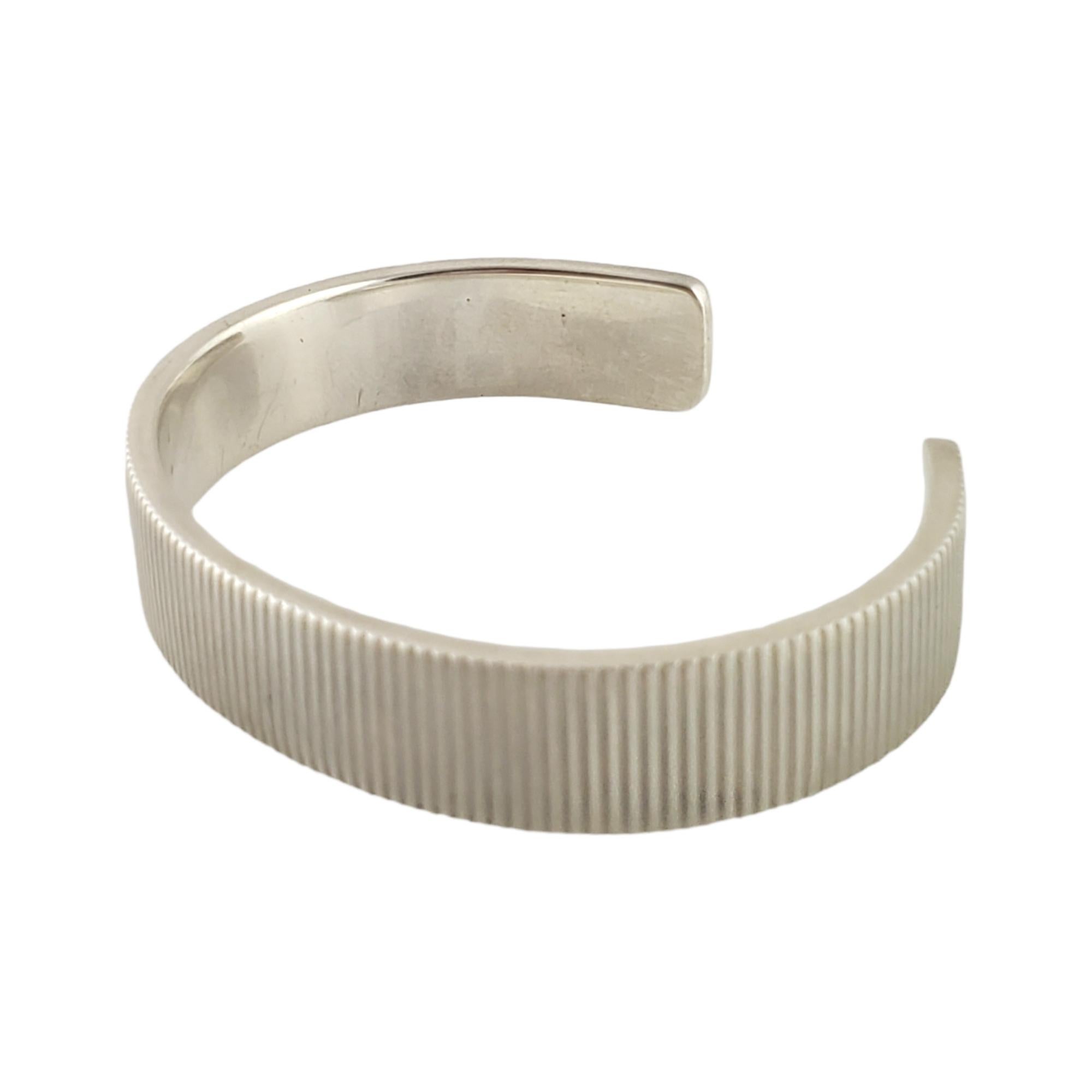 Sterling Silver Coin Edge Cuff Bracelet by Tiffany & Co, circa 2003.

Authentic Tiffany cuff bracelet featuring a ribbed design. Tiffany pouch and box not included.

Measures approx 6