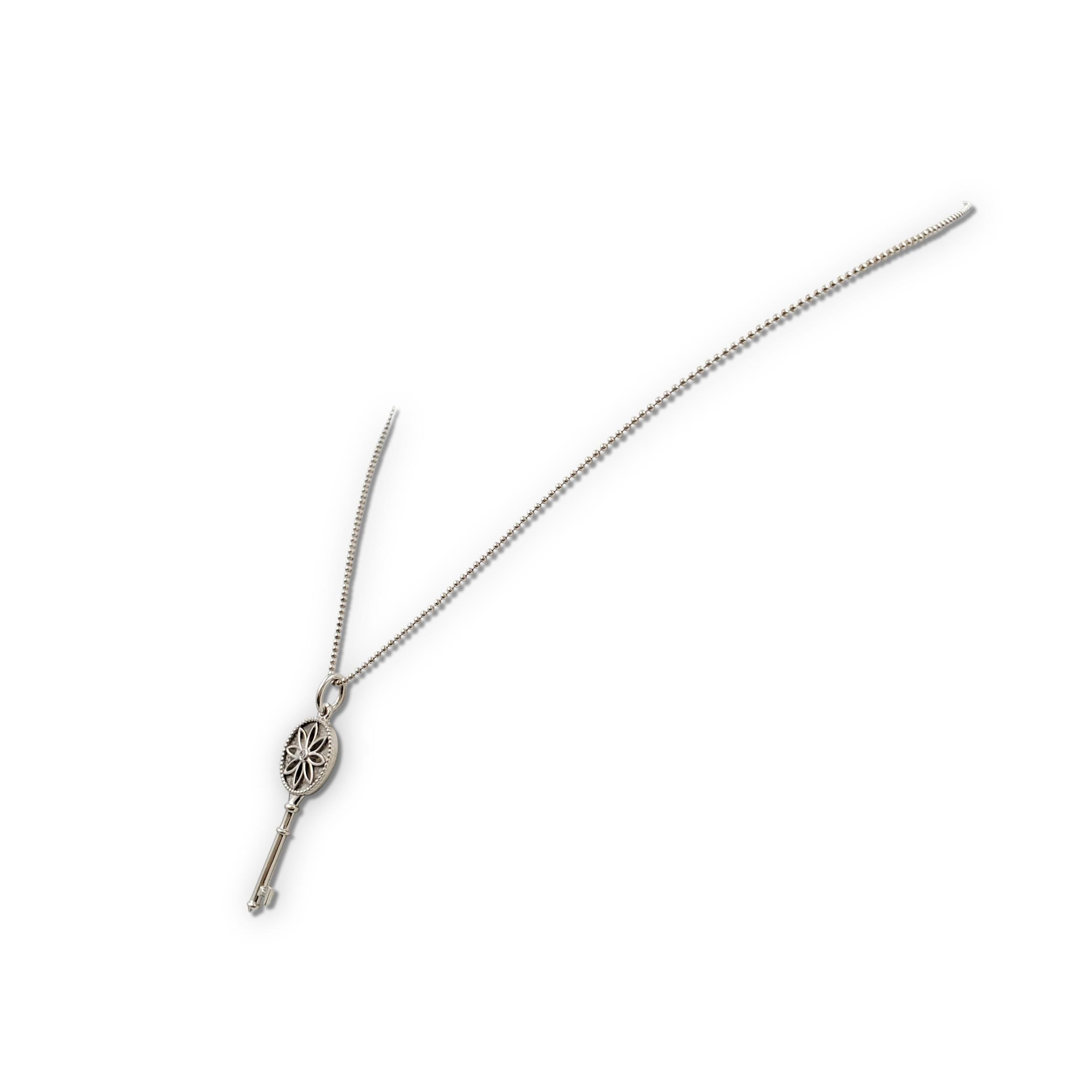Authentic Tiffany & Co. 'Daisy Key' pendant from the Tiffany Keys collection crafted in sterling silver and ser with a single round brilliant cut diamond. The pendant hangs from a delicate Tiffany & Co. sterling silver beaded chain necklace that
