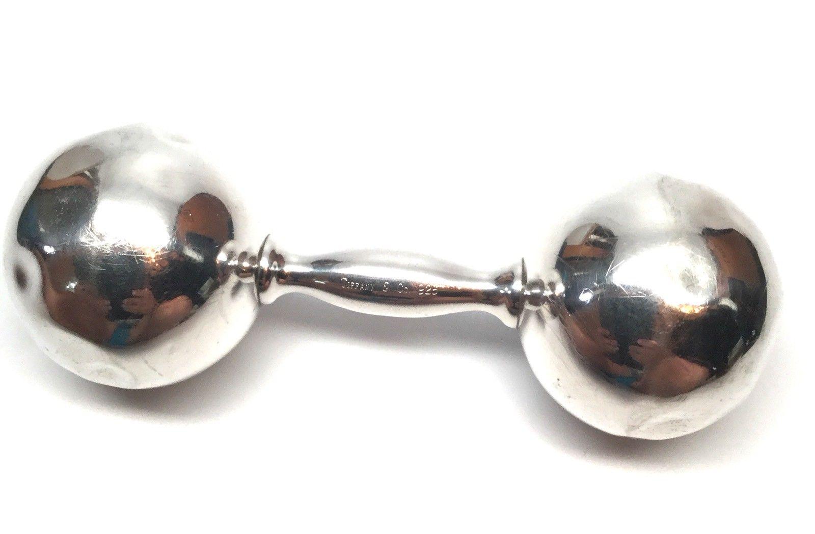 Tiffany & Co. sterling silver dumbbell baby rattle. This is a beautiful and charming sterling silver dumbbell baby rattle designed by Tiffany & Co. It has a soft sweet jingle when you shake it. Measures: Approximate 5 inches long. Weight: 72.9 g /