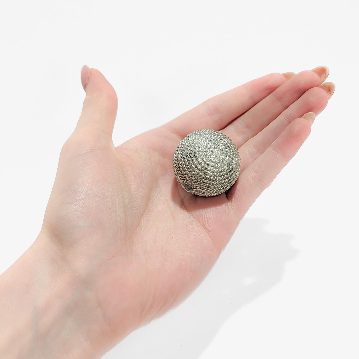 A fine figural vanity box or pill box.

By Tiffany & Co.

In sterling silver.

In the form of a coiled ball of rope (or ball of yarn).

Marked to the interior rim with Tiffany & Co. / Sterling / 925 / Italy.

Simply a great Tiffany box!

Date:
20th