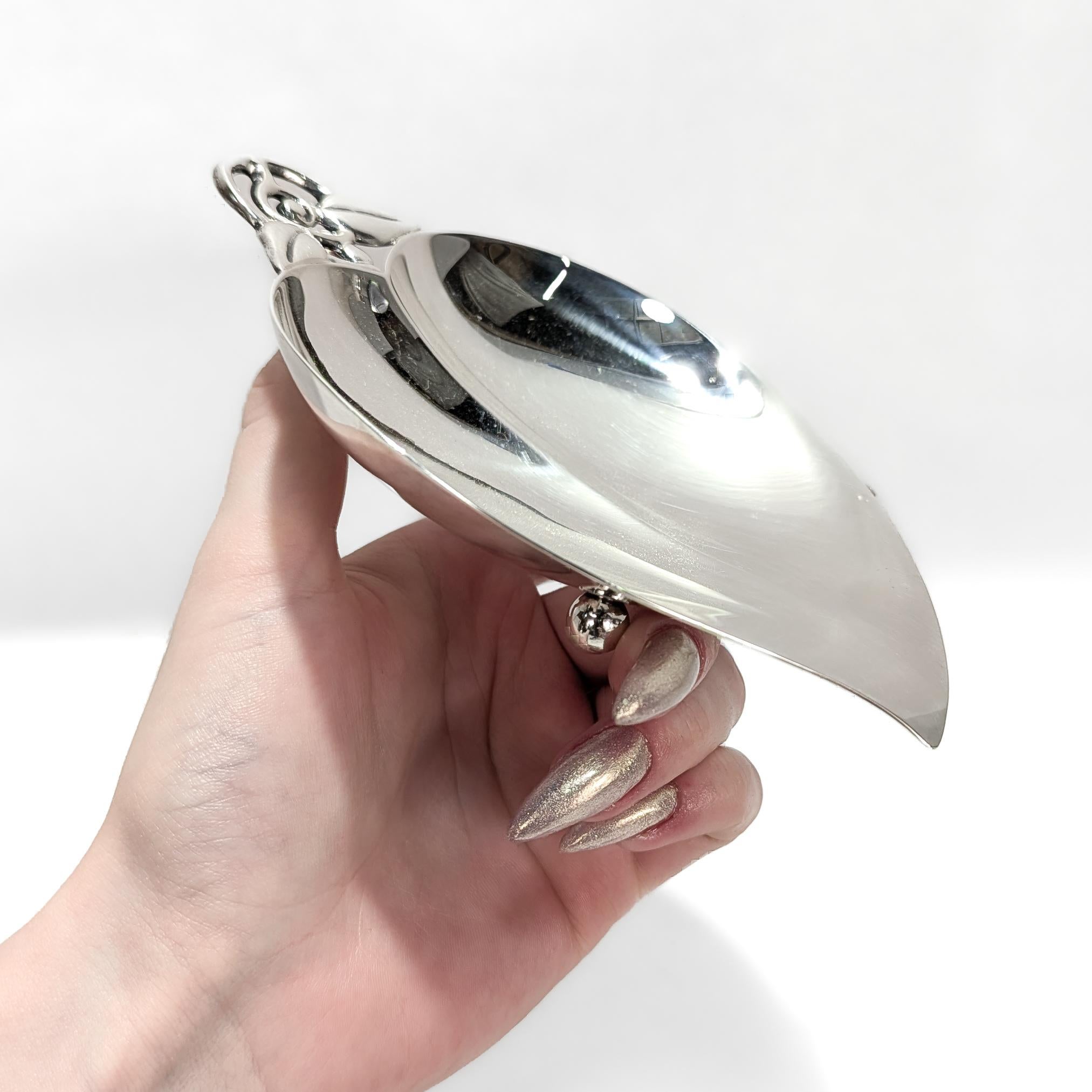 A fine signed silver dish or vide poche.

By Tiffany & Co.

In sterling silver. 

Pattern no. 22885.

In the form of a heart-shaped leaf with a figural stem and leaf openwork handle and two ball feet.

Marked to the base.

Simply a wonderful Tiffany