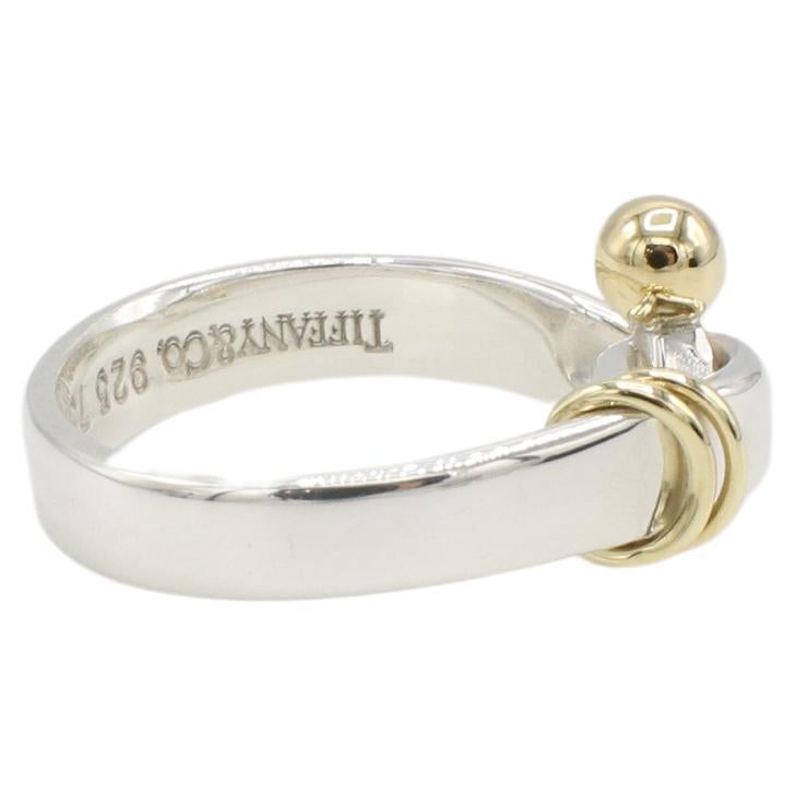 Tiffany & Co. Sterling Silver & Gold Buckle Hook & Eye Ring 
Metal: Sterling silver & 18k yellow gold
Weight: 3.97 grams
Size: 4.5 (US)
Signed: Tiffany & Co. 925 750
