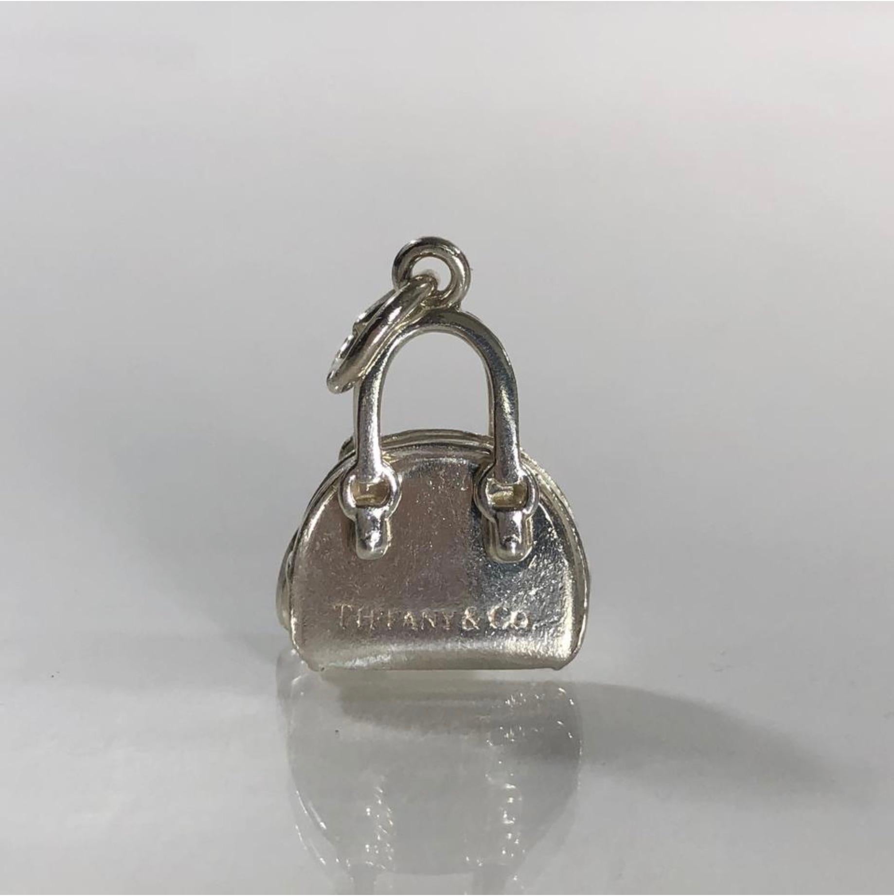MODEL - Tiffany & Co Sterling Silver Handbag Charm or Pendent w Hanging Heart 

CONDITION - Exceptional!

SKU - 1523

ORIGINAL RETAIL PRICE - $195 + tax

DIMENSIONS - L.5 x H.8 x D.25

CLOSURE TYPE - Not Applicable. Bail for hanging to a bracelet or