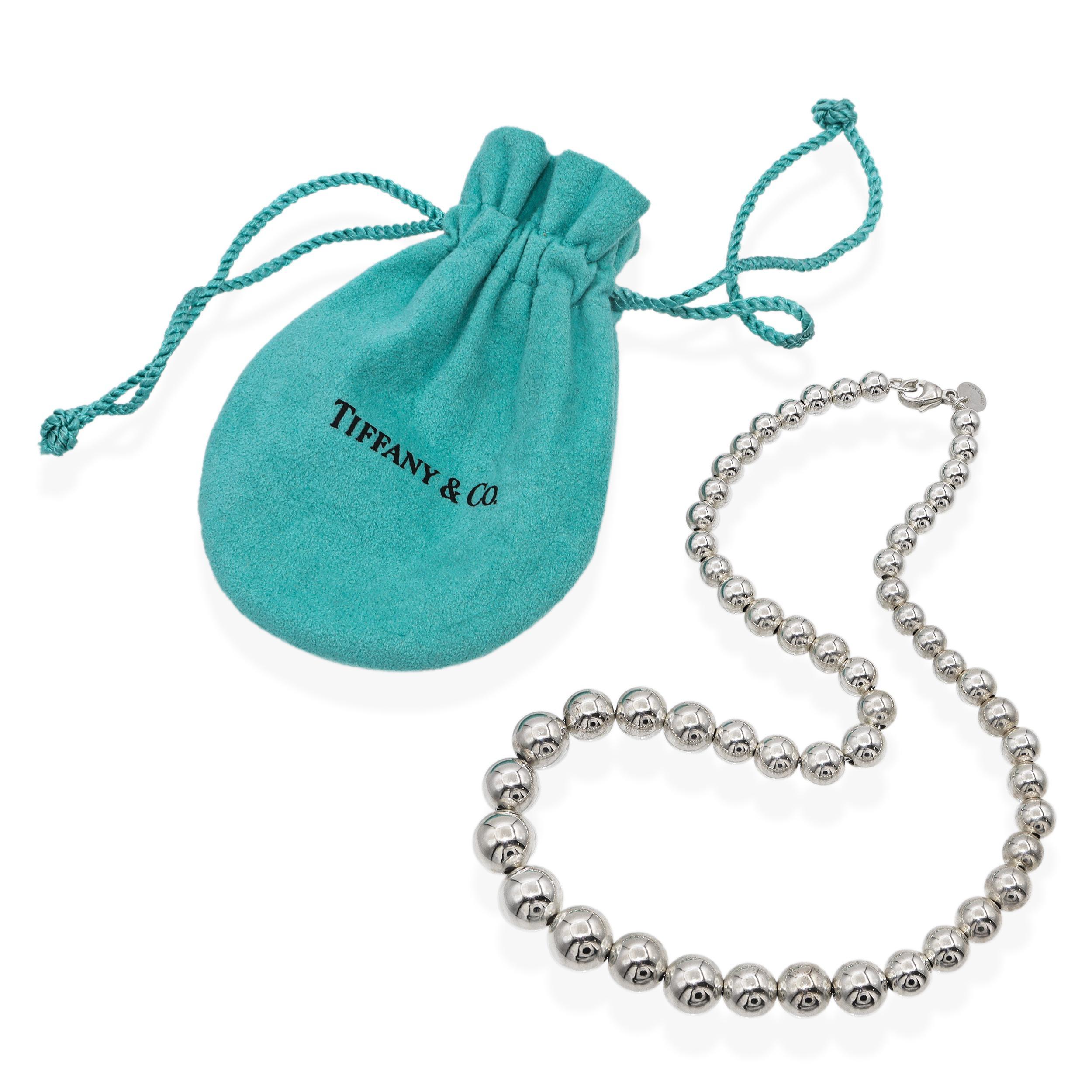 Questa elegante collana di Tiffany & Co. è realizzata in argento sterling e presenta un filo di perline sferiche lucide che aumentano gradualmente di dimensione verso il centro, creando un design raffinato ed equilibrato. La collana è rifinita con
