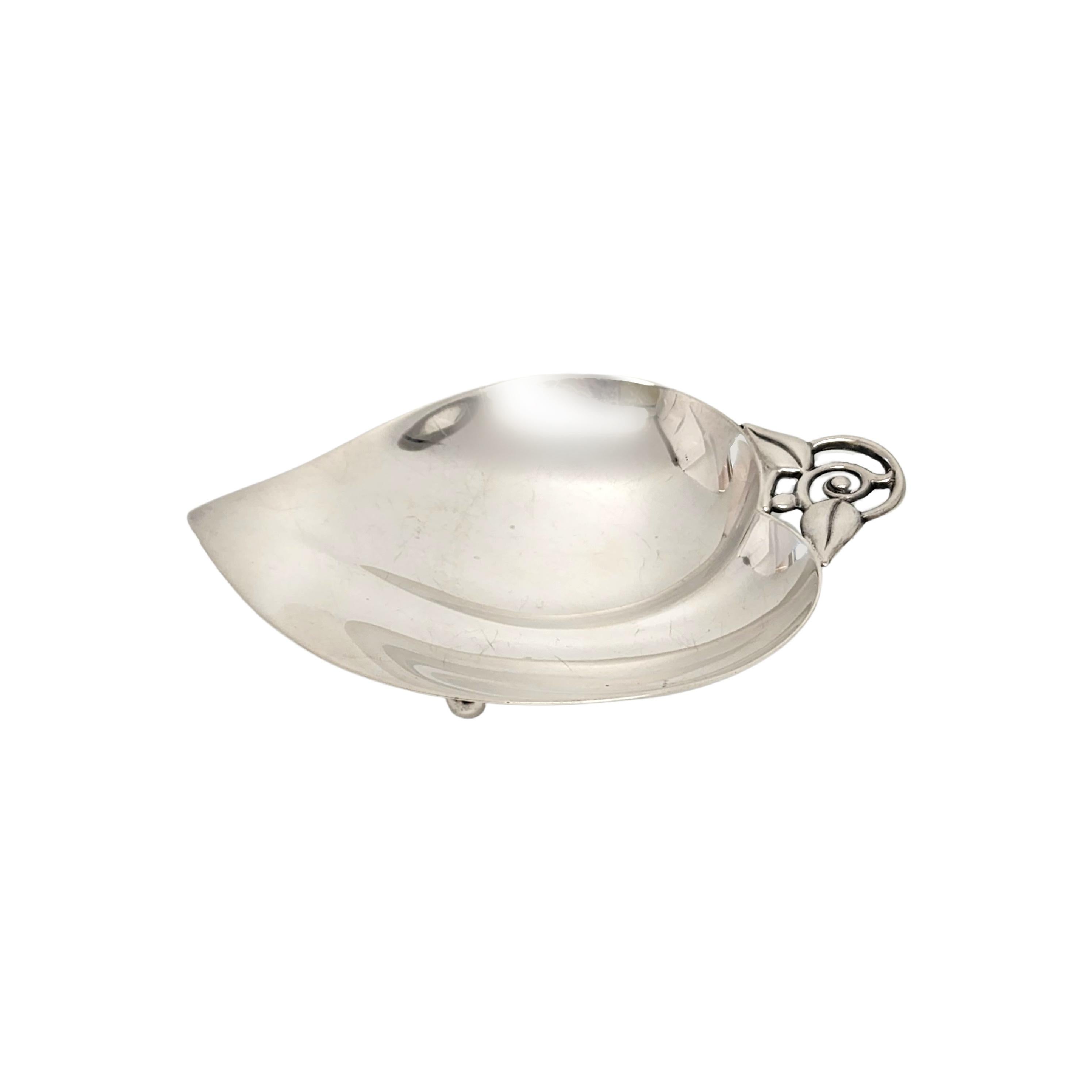 Tiffany & Co sterling silver small apple/heart shaped dish.

A beautiful sterling silver apple or heart shaped dish featuring an open work leaf handle and 2 ball feet underneath. The M hallmark dates this piece to manufacture under the directorship