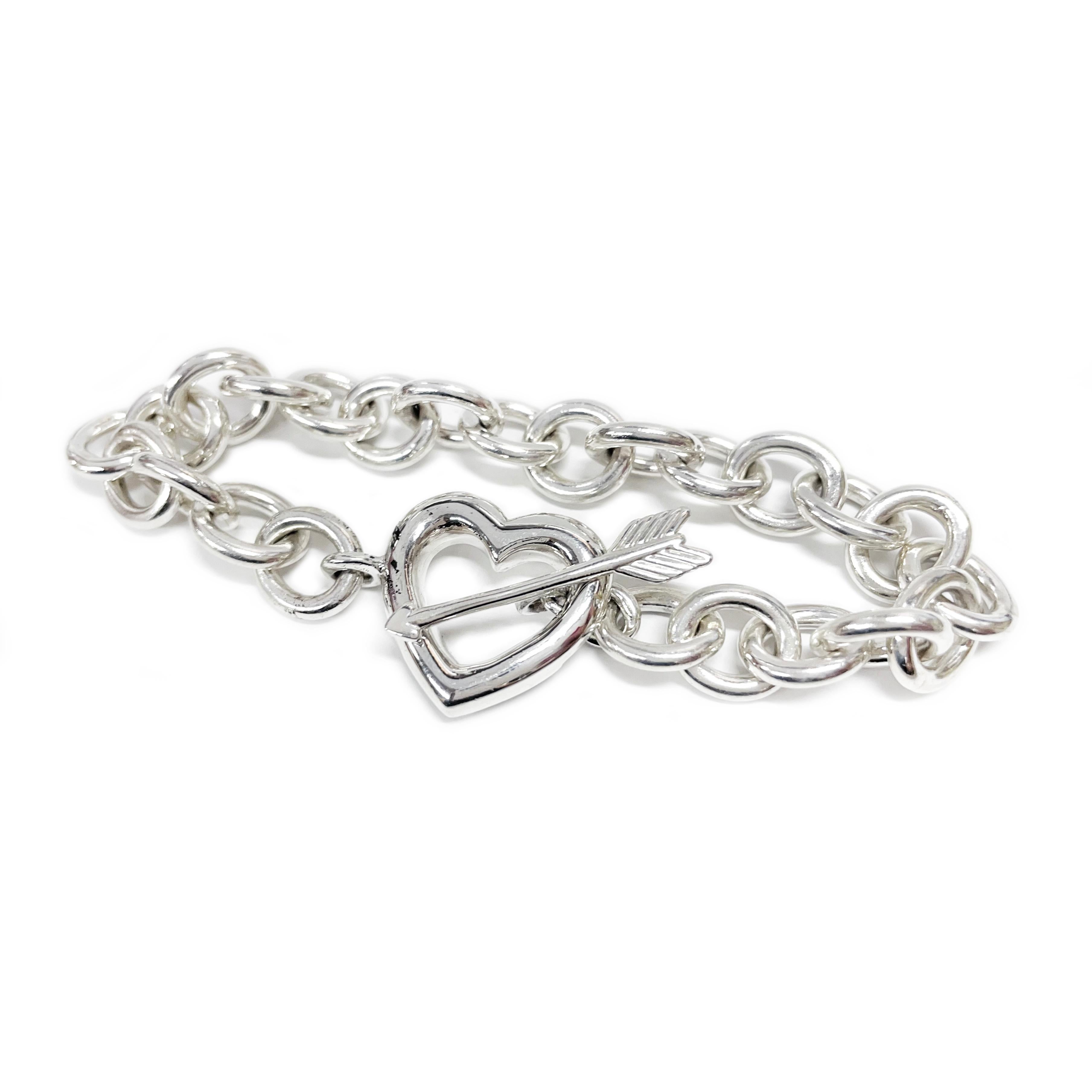 Tiffany & Co. Sterling Silver Heart Arrow Bracelet. The bracelet features a heavyweight link chain with an open heart and arrow toggle clasp. There are slight surface scuffs but no major scratches. The links measure approximately 9mm wide and the