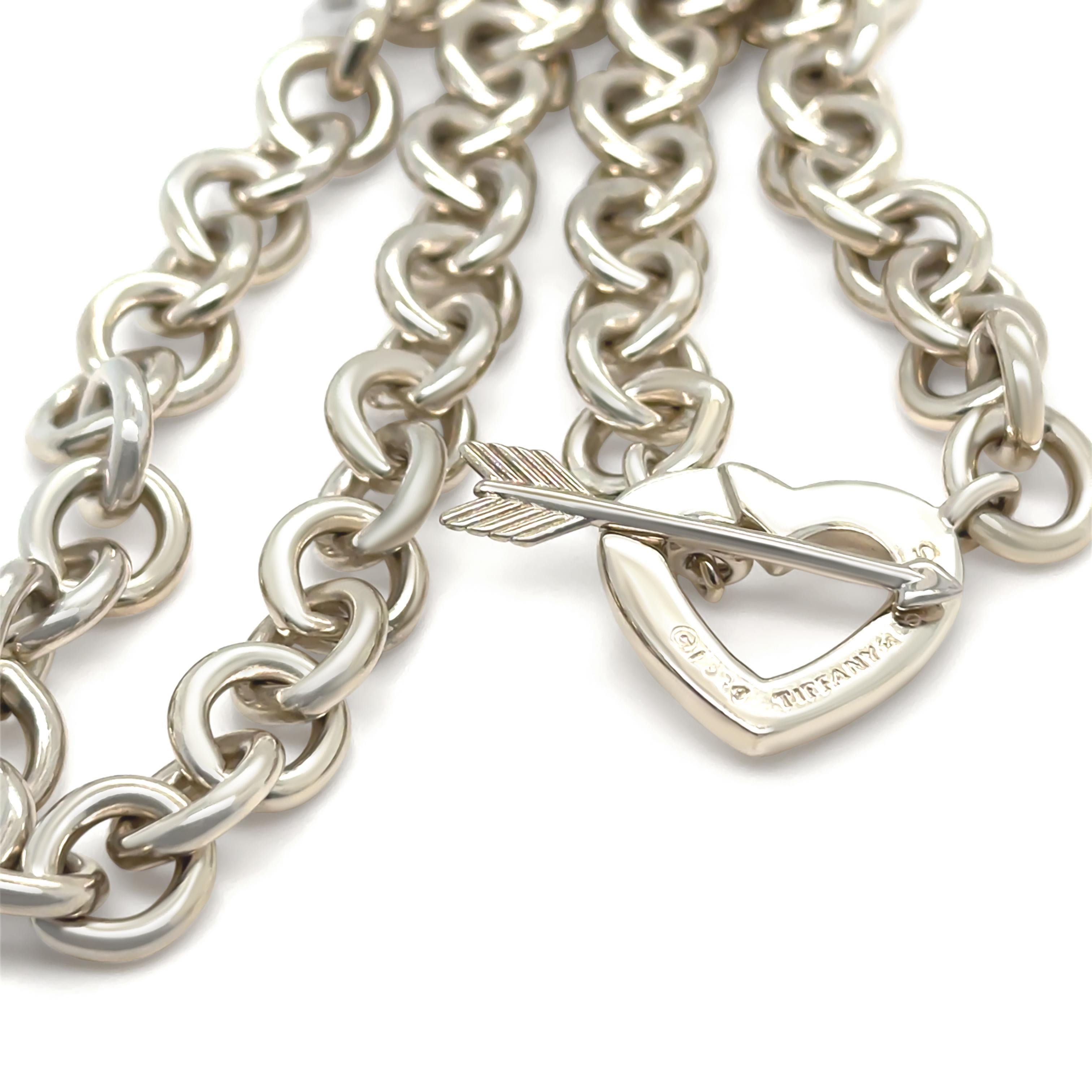 This striking Tiffany & Co. Heart Arrow Toggle Choker Necklace is crafted from high-quality 925 sterling silver, showcasing bold elegance and timeless appeal. The design features a heart and arrow motif with a secure toggle clasp, offering a