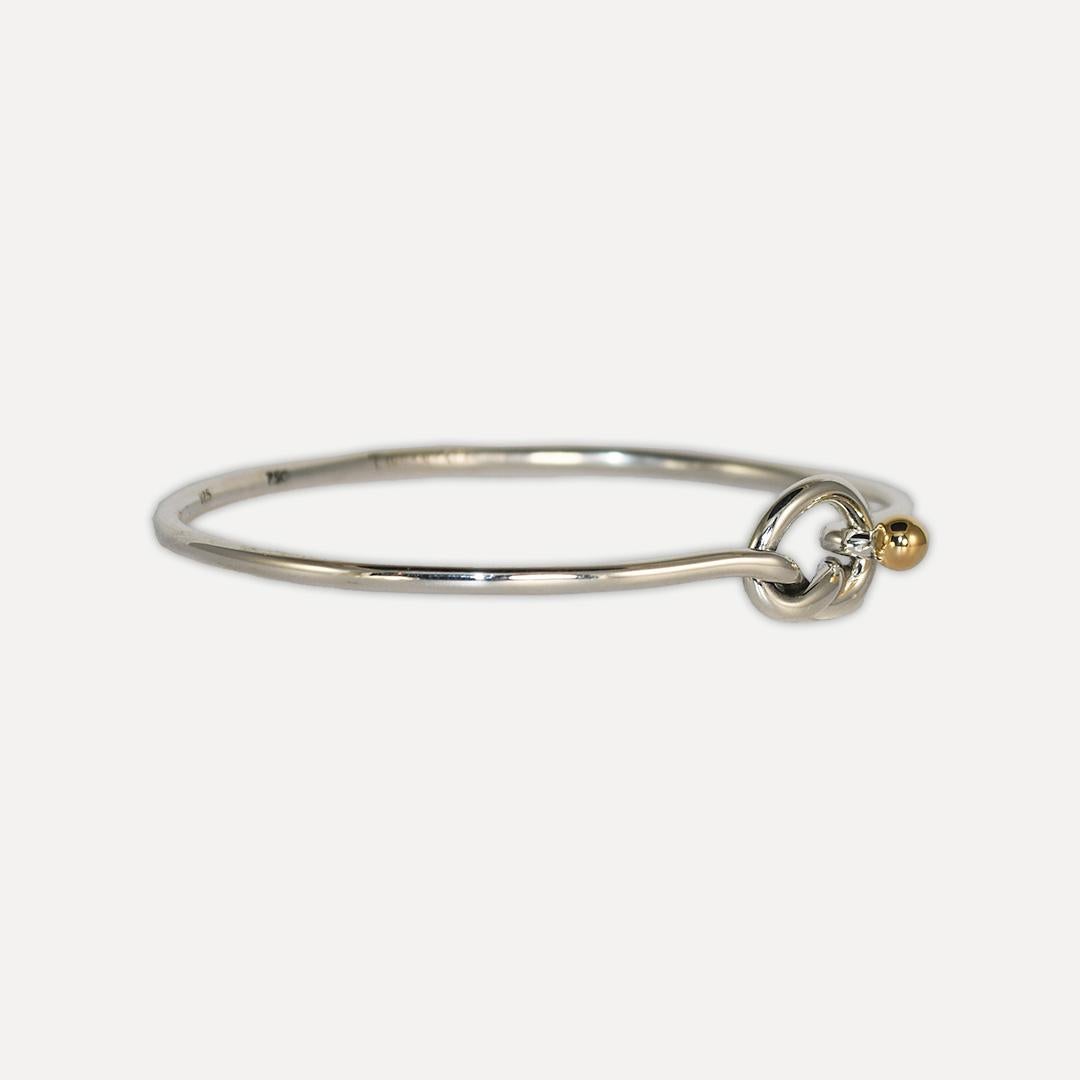 Ladies' Tiffany & Co sterling silver heart cuff bracelet with 18k accent.
Stamped .925, 750, Tiffany Co.
The bangle measures 2mm thick.
There is a heart shape at the top with an 18k yellow-gold accent.
The bracelet opens and clips shut at the