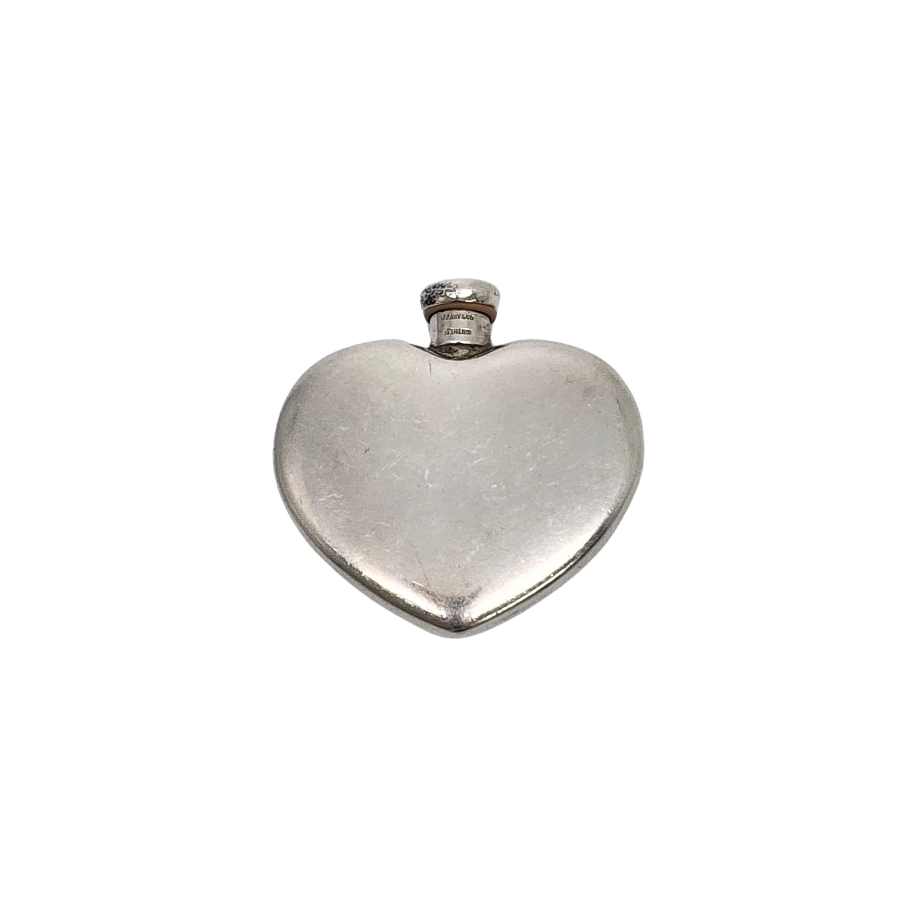 Vintage sterling silver heart perfume bottle by Tiffany & Co with monogram.

Monogram appears to be CMG

This beautiful scent bottle features a heart shaped bottle with smooth polished design on both sides and a screw-off top with dauber attached.