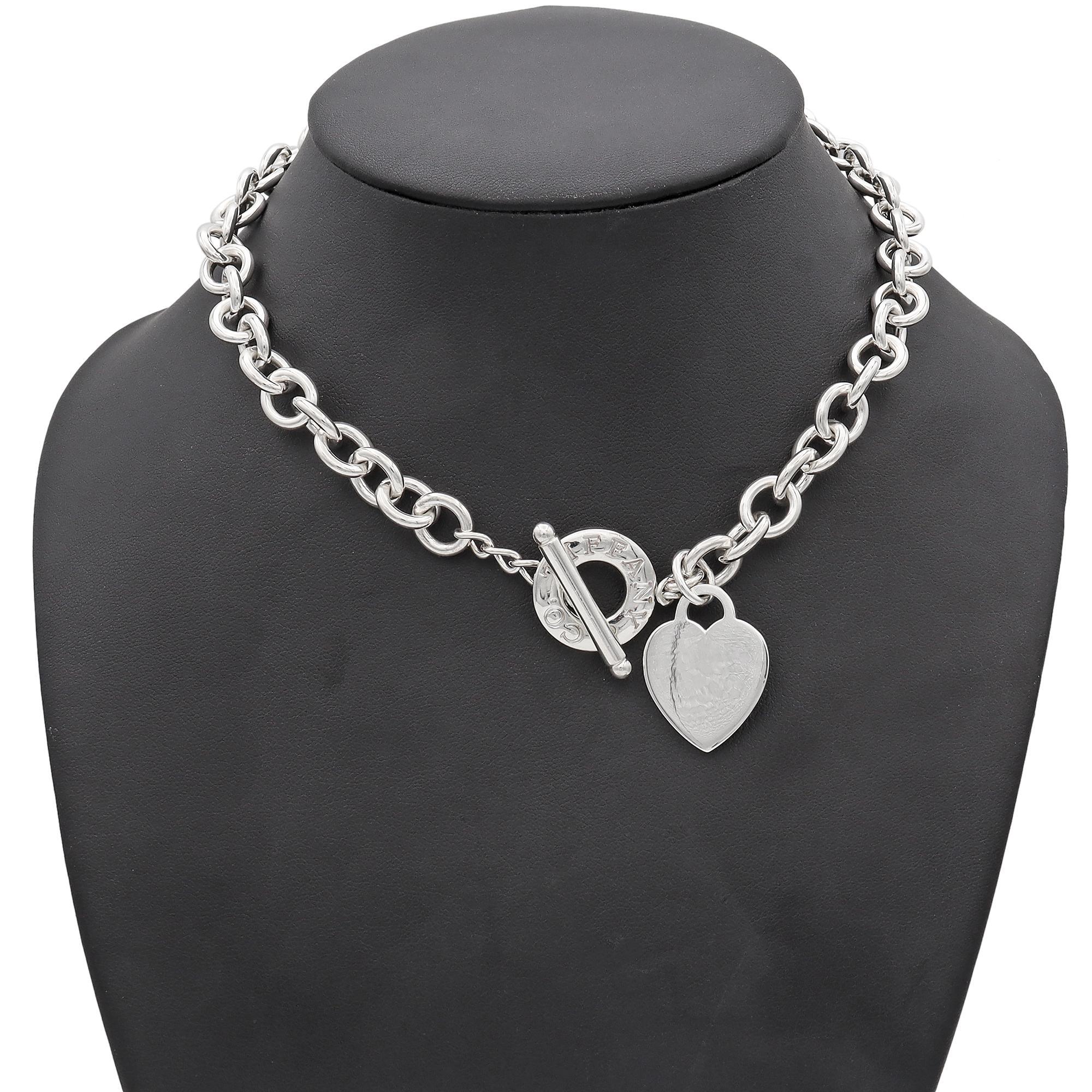 Una collana in argento sterling di Tiffany & Co. Questo pezzo elegante presenta un classico design a catena con maglie intrecciate, che crea un look versatile e senza tempo. La collana è impreziosita da un ciondolo a forma di cuore che aggiunge un