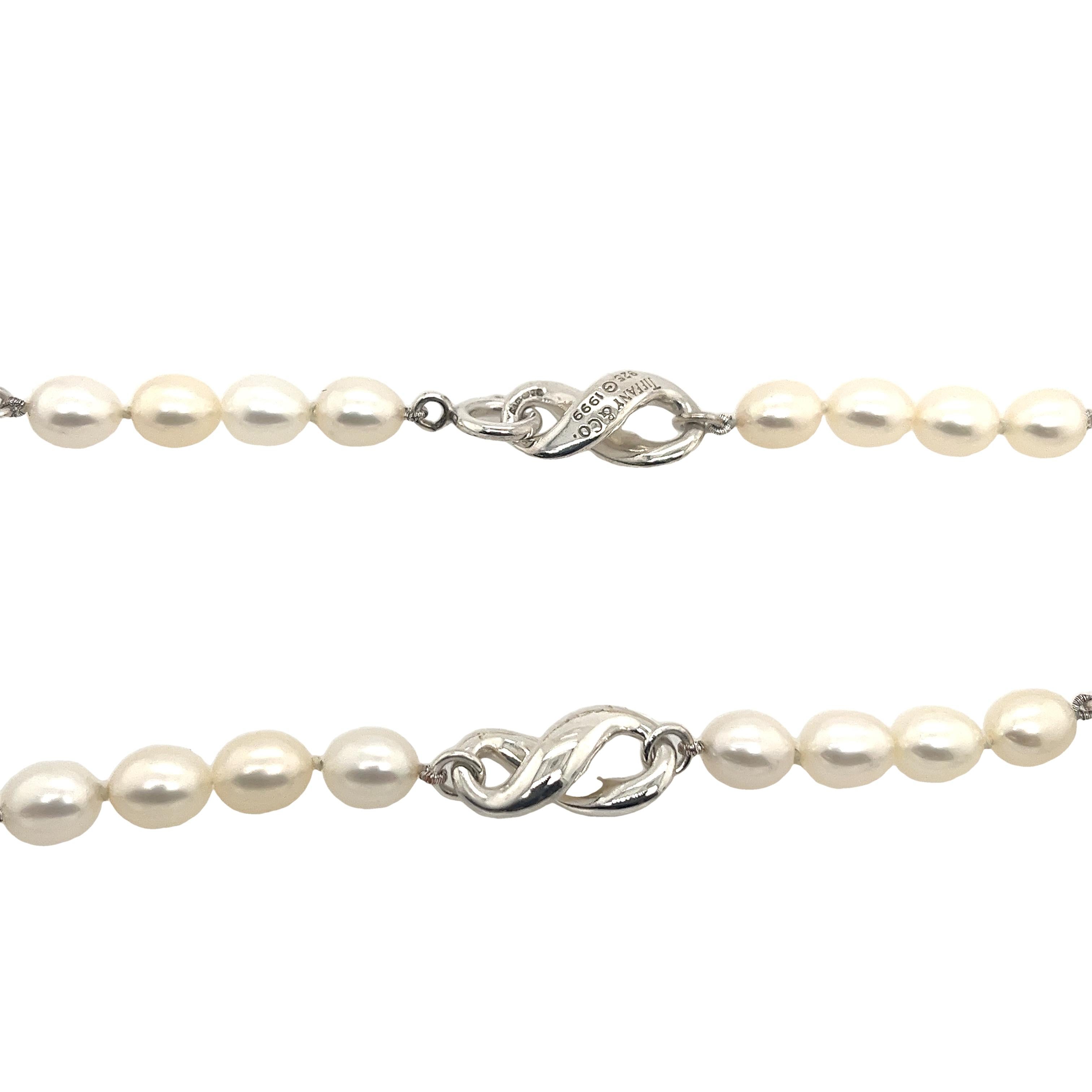 Introducing the epitome of elegance the Tiffany & Co sterling silver infinity figure white pearl necklace.  
This breathtaking necklace combines timeless beauty and contemporary style in one enchanting piece.
It is engraved: TIFFANY & CO 925 
1999.
