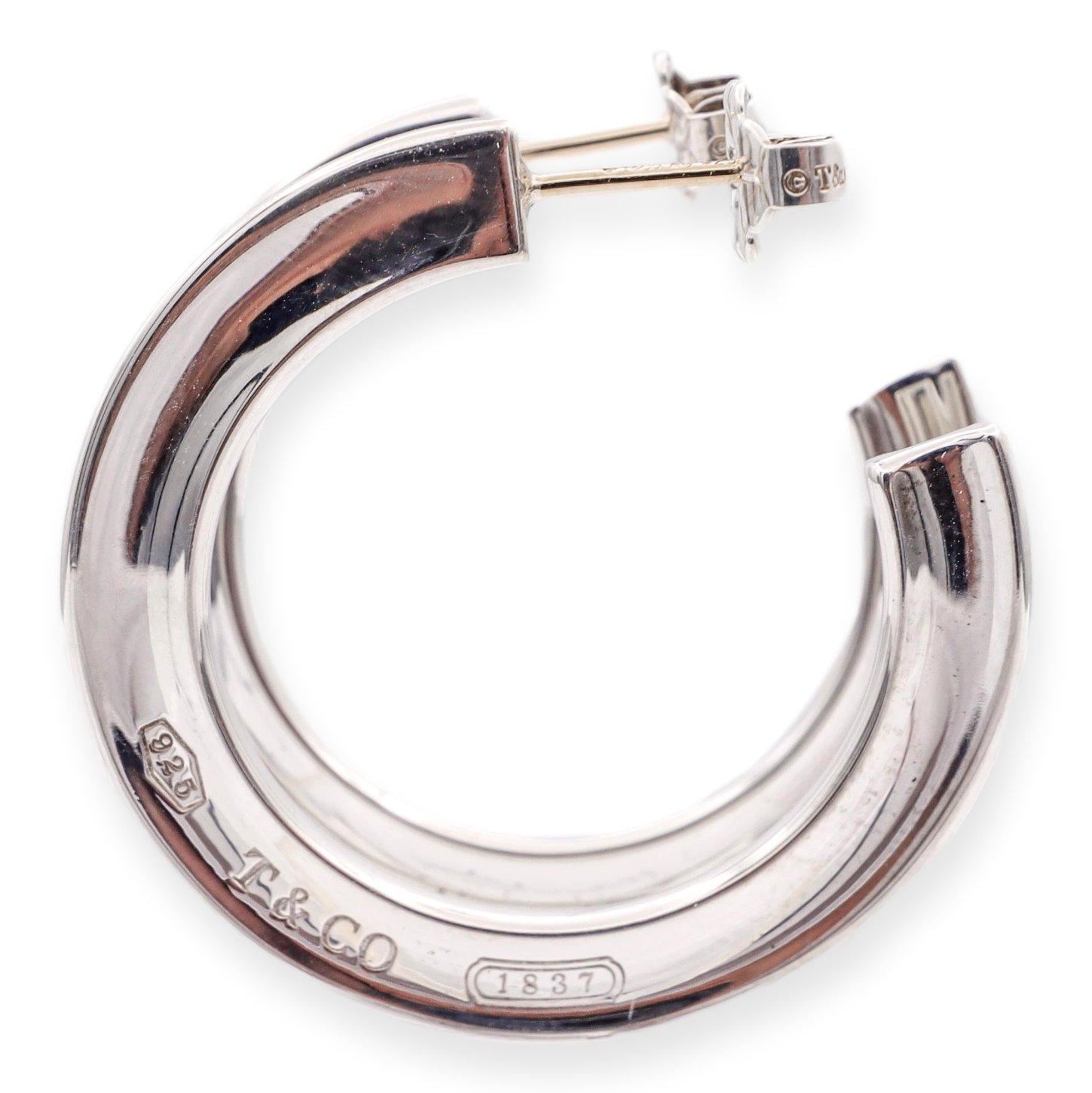 Tiffany & Co. pair of hoop earrings from the 1837 collection finely crafted in sterling silver featuring flat edges and posts with butterfly backs. The earrings measure 1.25 inches in diameter and hang 1.25 inches from earlobe. Fully hallmarked with