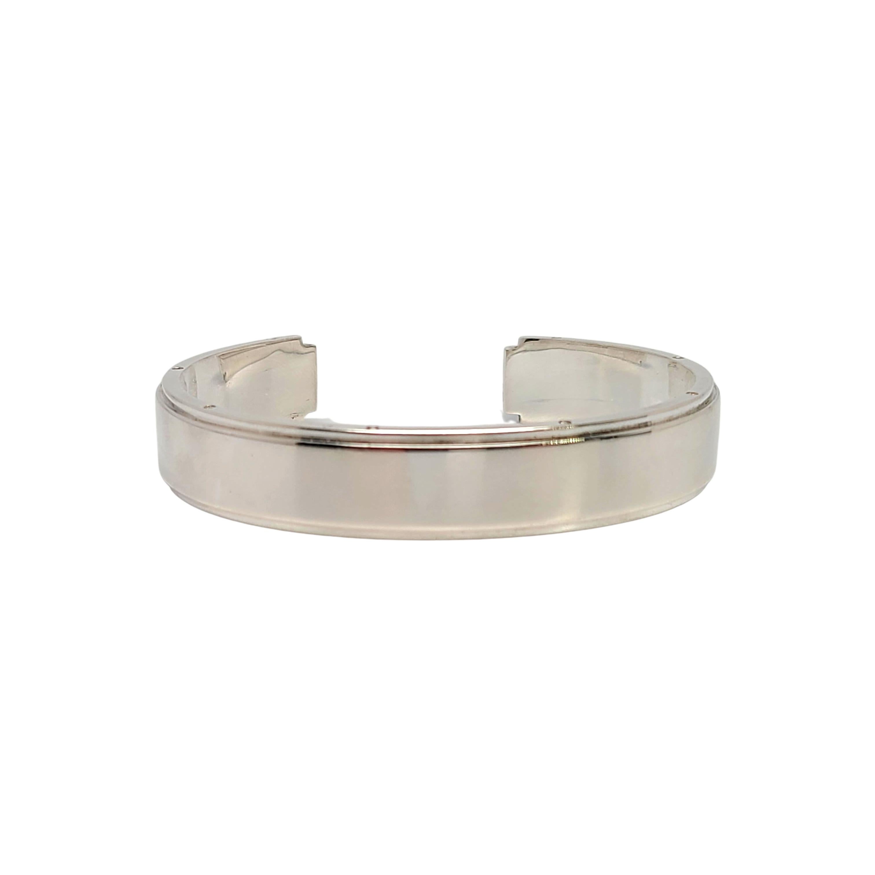 Tiffany & Co sterling silver Metropolis cuff bracelet.

Authentic Tiffany sterling silver Metropolis cuff features a polished center, recessed edges and small rivet screws all around the edges on both sides of the ring. Tiffany pouch and box not