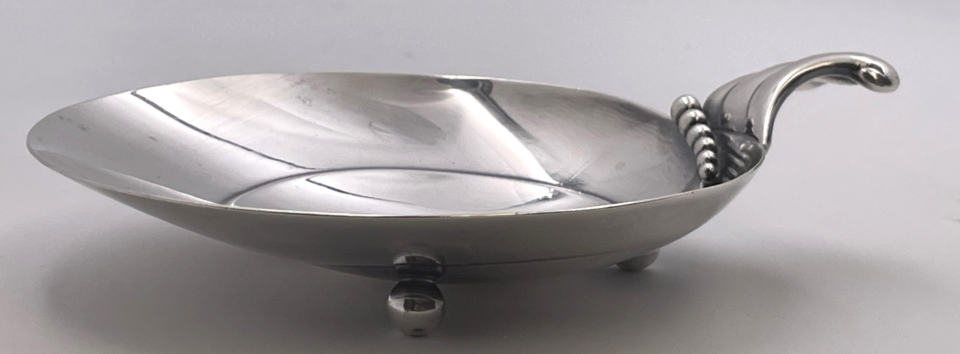 Plato para caramelos o frutos secos de plata de ley de Tiffany & Co., de estilo moderno de mediados de siglo y elegante diseño que recuerda a una concha de nautilo, con motivos de cuentas en relieve y asa de inclinación geométrica, apoyado sobre 3