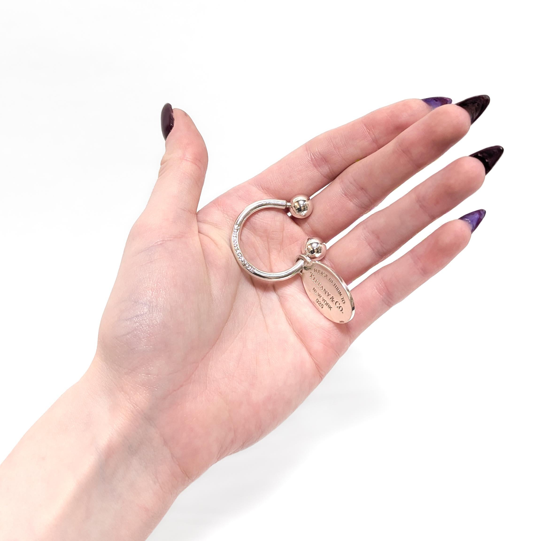 A very fine signed silver key holder.

By Tiffany & Co.

In sterling silver.

One of the ball shaped terminals is threaded and can be removed to add/remove keys from the ring.

The oval shaped tag reads: 'Please Return to Tiffany & Co. / New York /