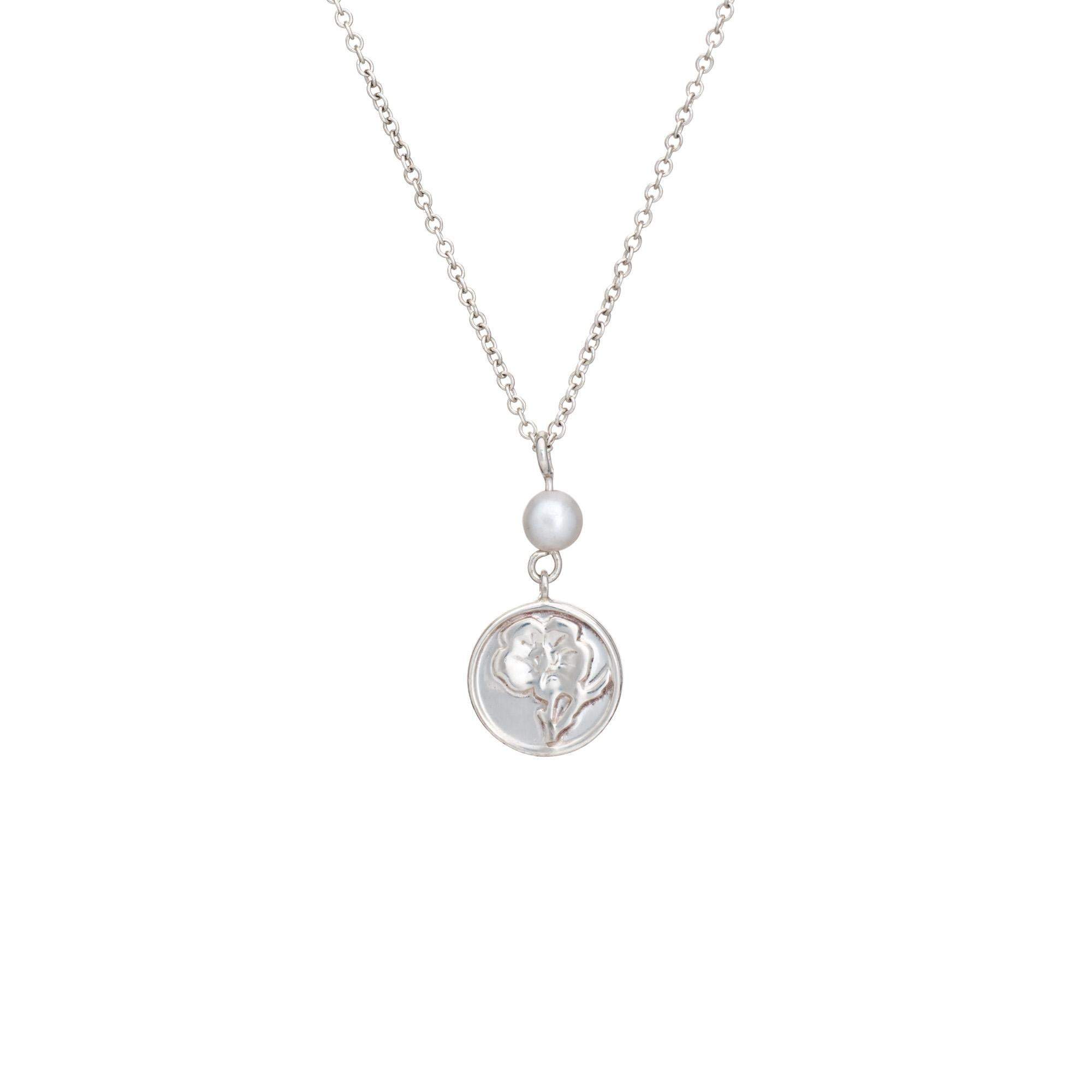 Elegante collar en forma de flor Tiffany & Co de segunda mano fabricado en plata de ley.  

El pequeño disco de plata de ley de doble cara de 10 mm resalta una hermosa flor (por ambos lados), acentuada con una pequeña perla cultivada de 4 mm. Mide