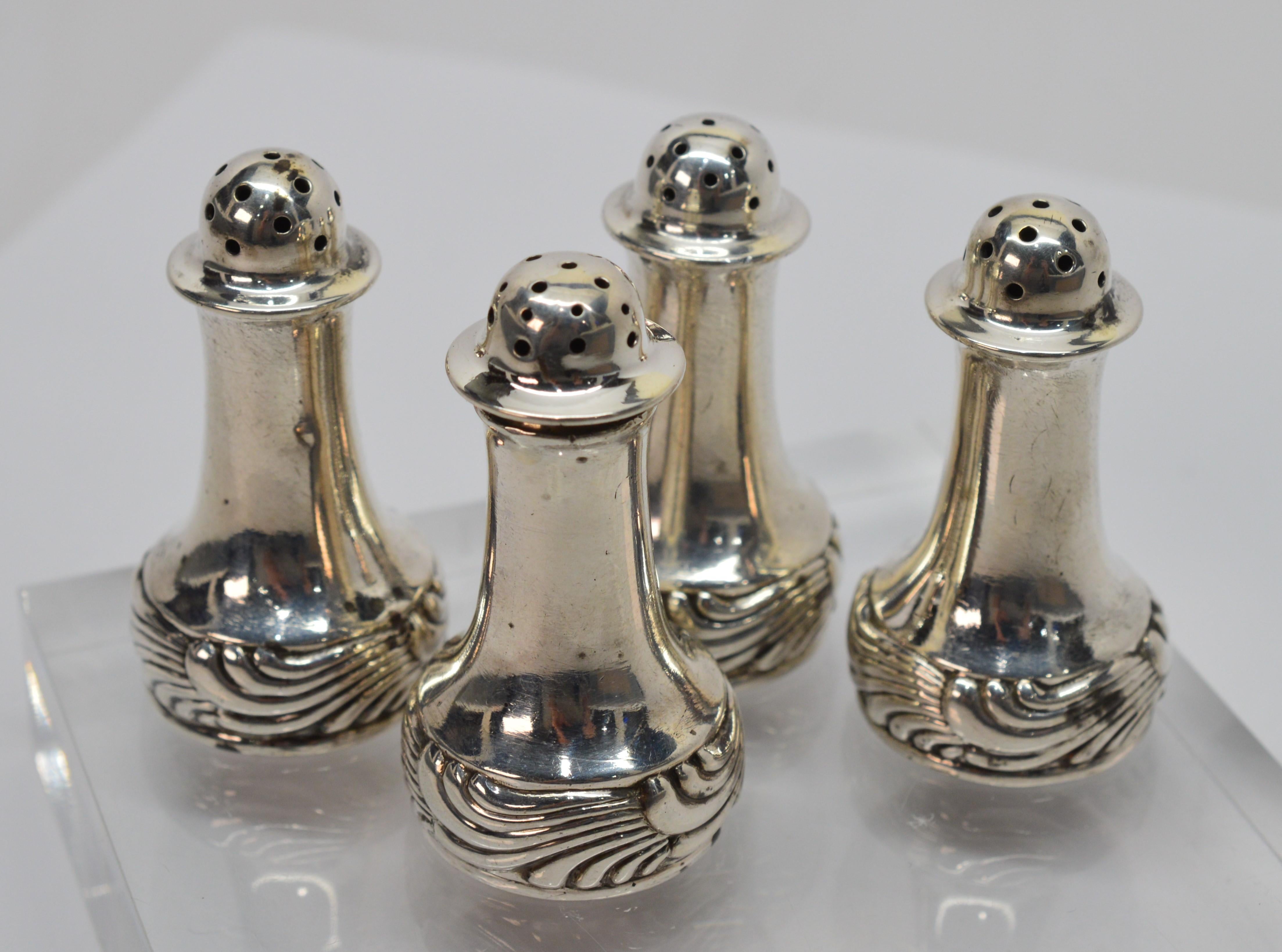 Set your table in style with two pair of vintage Tiffany & Co. salt and pepper shakers. This early 20th century set of four sterling silver shakers is decorated with an attractive scroll design that would complement any dinnerware style. The shakers