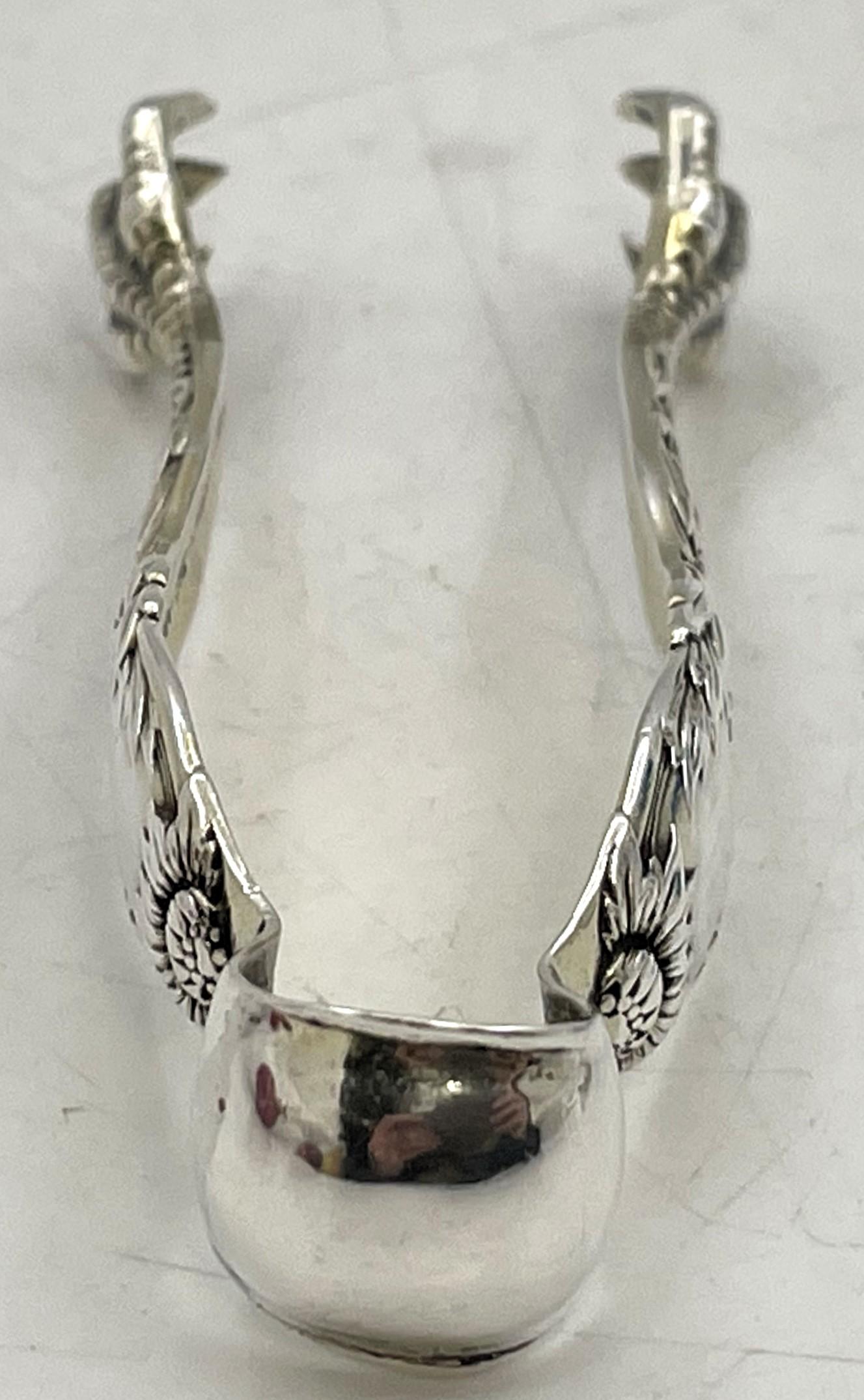 Pinzas de azúcar de plata de ley de Tiffany & Co. en el célebre diseño Crisantemo de 1880. Mide 3 1/3'' de largo por 1 1/8'' por 1/2'' de alto, está ligeramente dorado en el interior y lleva los sellos que se muestran. 

La legendaria marca Tiffany