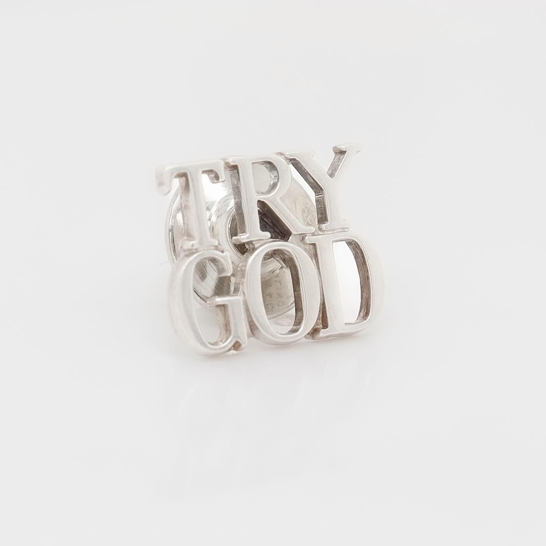 A fine, inspirational lapel pin.

By Tiffany & Co. 

In sterling silver.

In the form of the words: 'Try God'.

Simply a wonderful pin from Tiffany!

Date:
20th Century

Overall Condition:
It is in overall good, as-pictured, used estate condition.