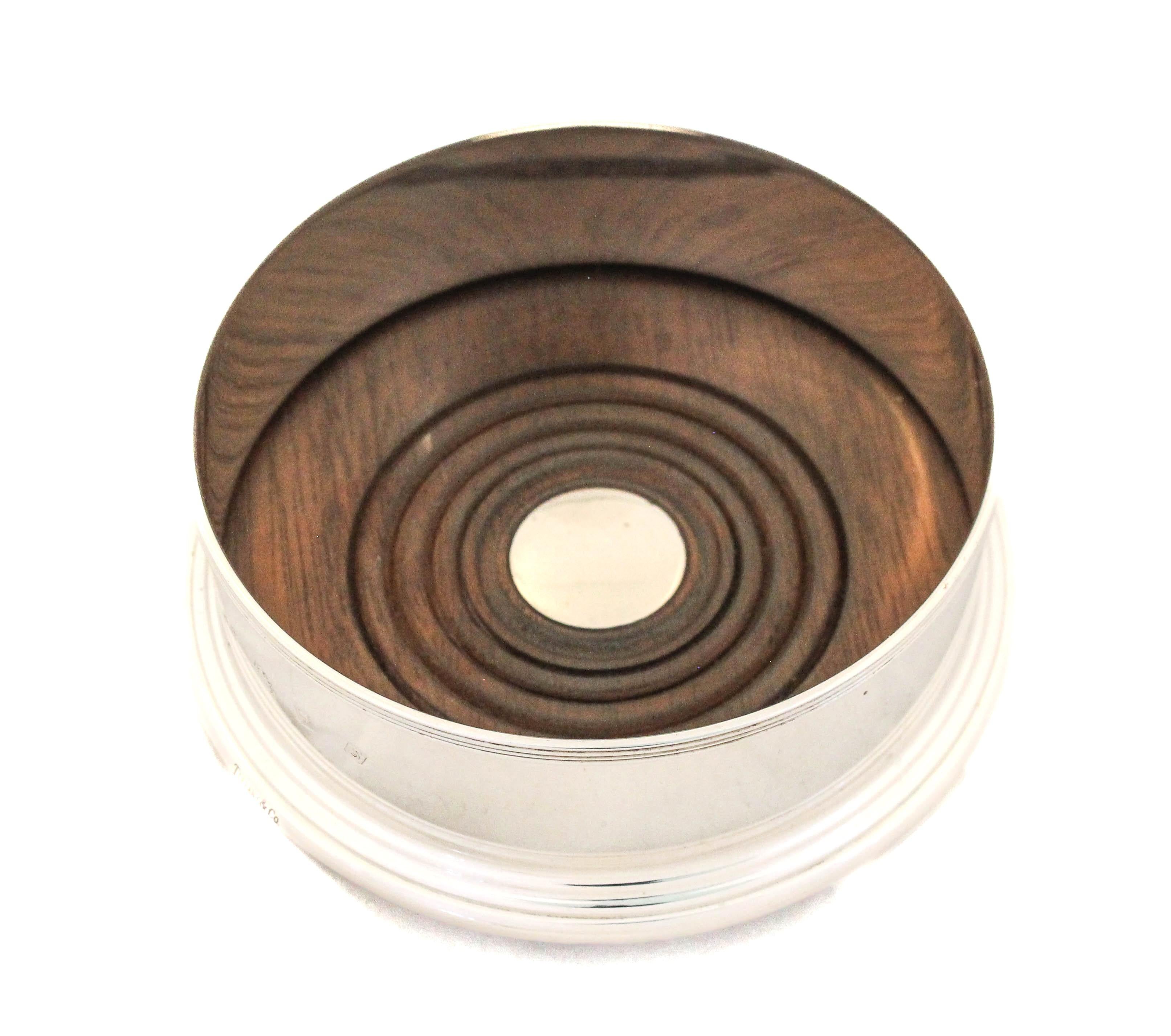 This sterling silver wine coaster was manufactured in England by Tiffany & Company.  The inside has a wood base to absorb condensation and has been re-stained in a walnut finish (like the original).  The bottom has a felt to prevent scratches on
