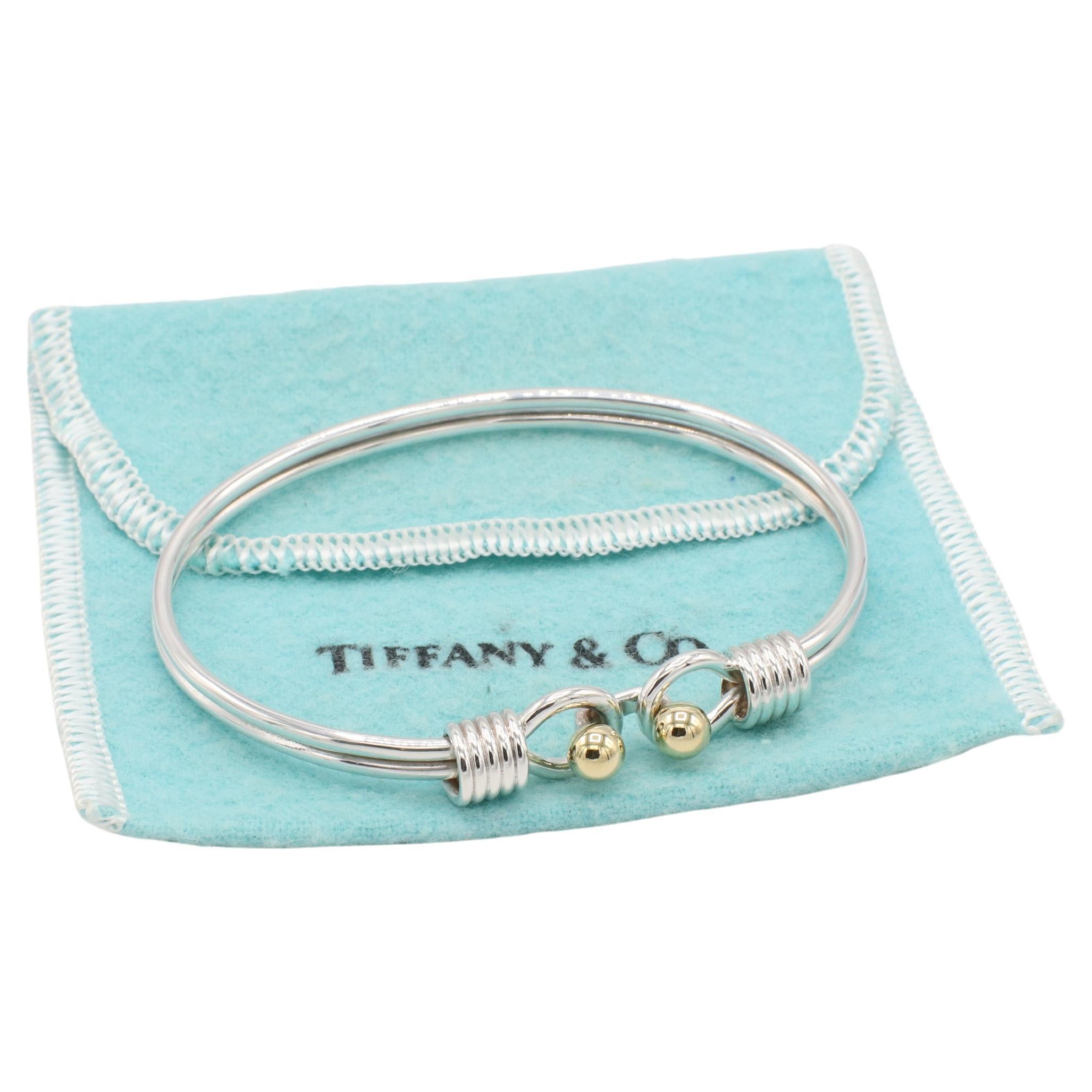 Tiffany & Co. Sterling Silver 18 Karat Yellow Gold Hook Bangle Cuff Bracelet 
Metal: Sterling silver & 18k yellow gold
Weight: 14.88 grams
Width: 4mm
Size: Fits approx. 6.75 inch wrist
Inside diameter: 62mm
Signed: Tiffany & Co. 925 750