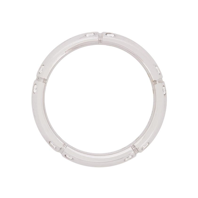 Realizzata in oro bianco 18 carati, questa fede nuziale appartiene alla collezione Streamerica di Tiffany & Co. Presenta un design a croce, con piccoli diamanti incastonati intorno alla fascia in corrispondenza delle punte della croce. In totale ci