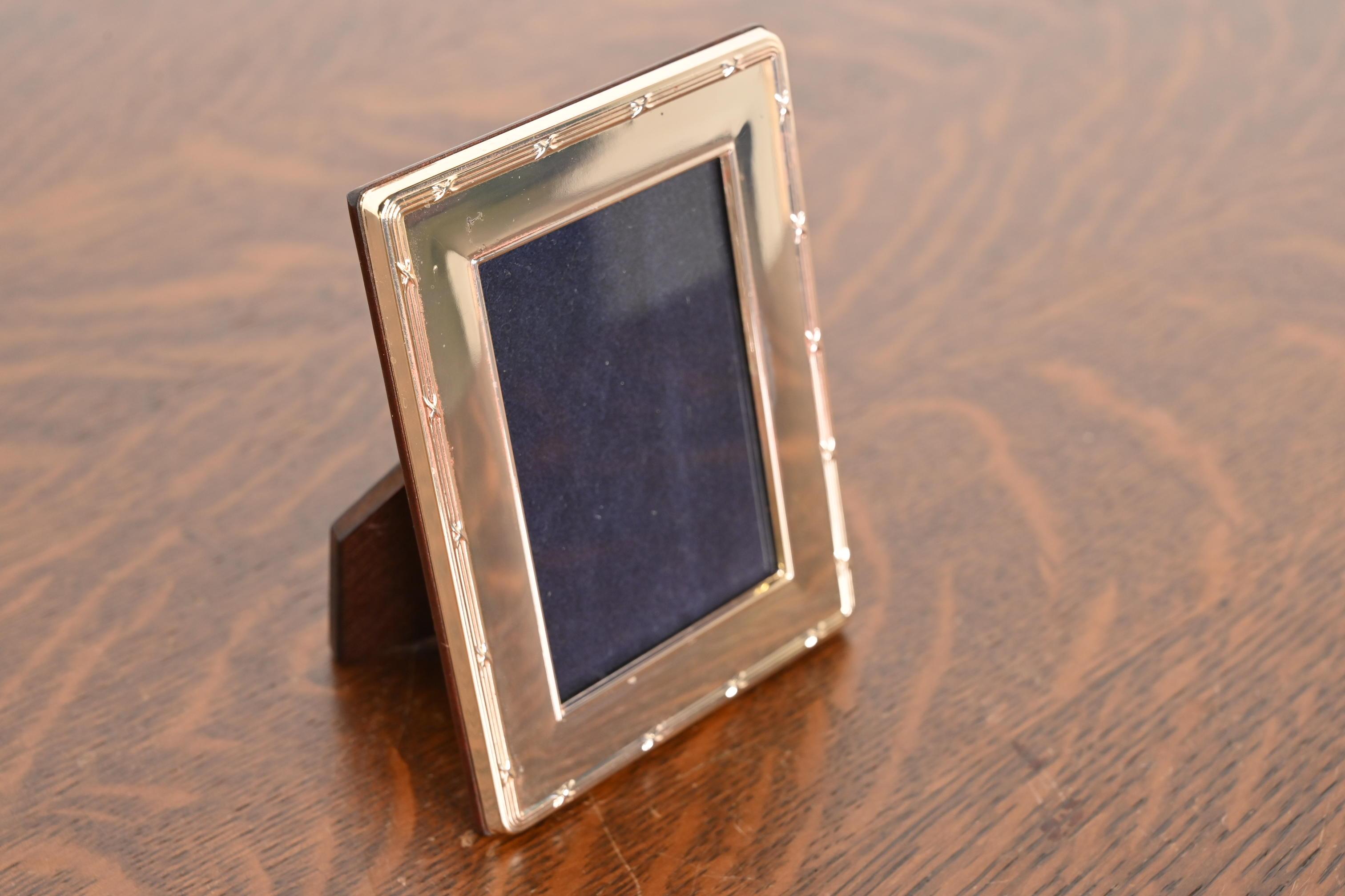 A lovely vintage Art Deco style sterling silver picture frame with blue velvet liner and mahogany backing

In the manner of Tiffany & Co.

England, Circa Late Century

Measures: 3.75