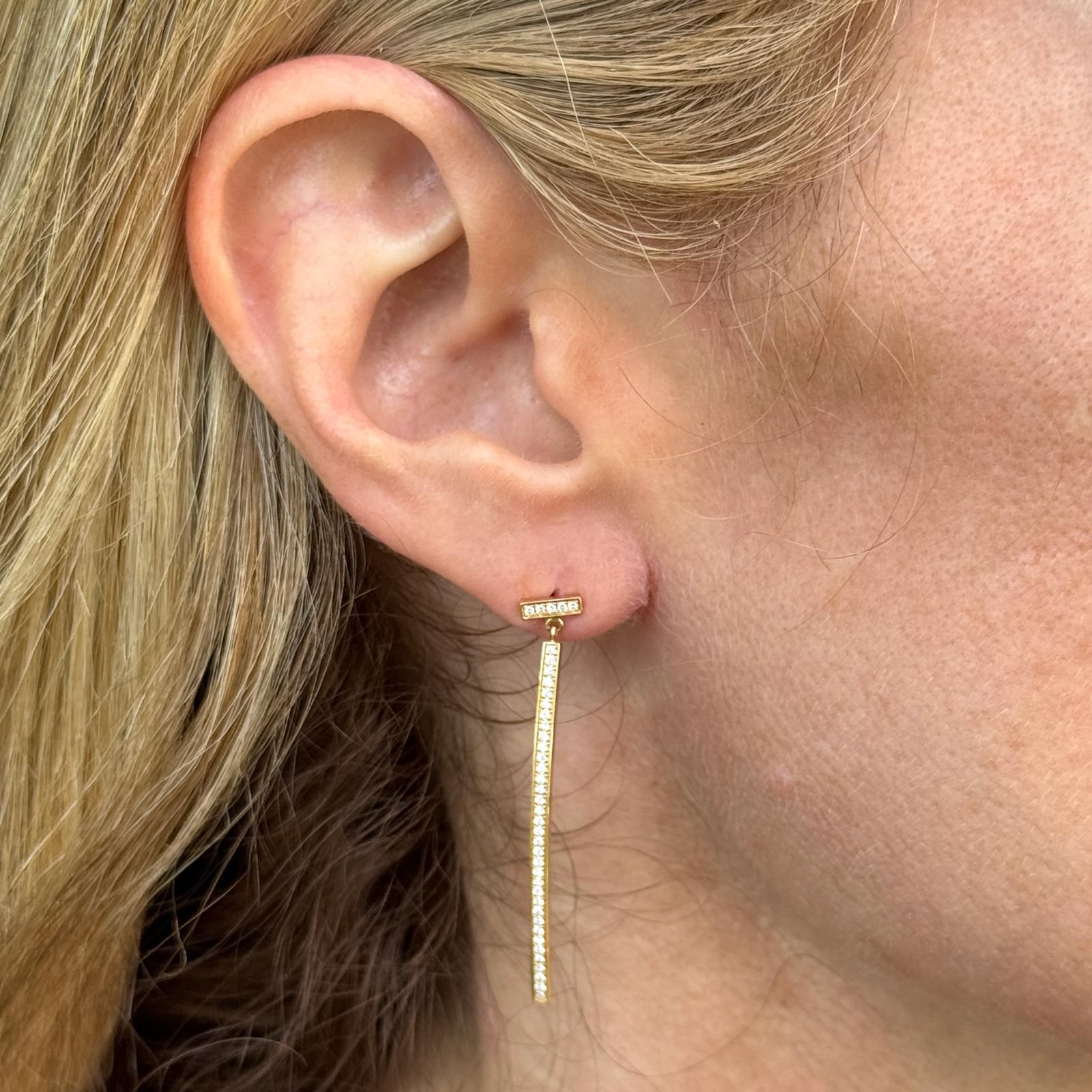 Moderni ed eleganti, questi orecchini a goccia T Bar in oro giallo 18 carati di Tiffany & Co. presentano un design lineare ed elegante, arricchito da diamanti rotondi con taglio a brillante per un totale di circa 0,21 carati. Con una lunghezza di