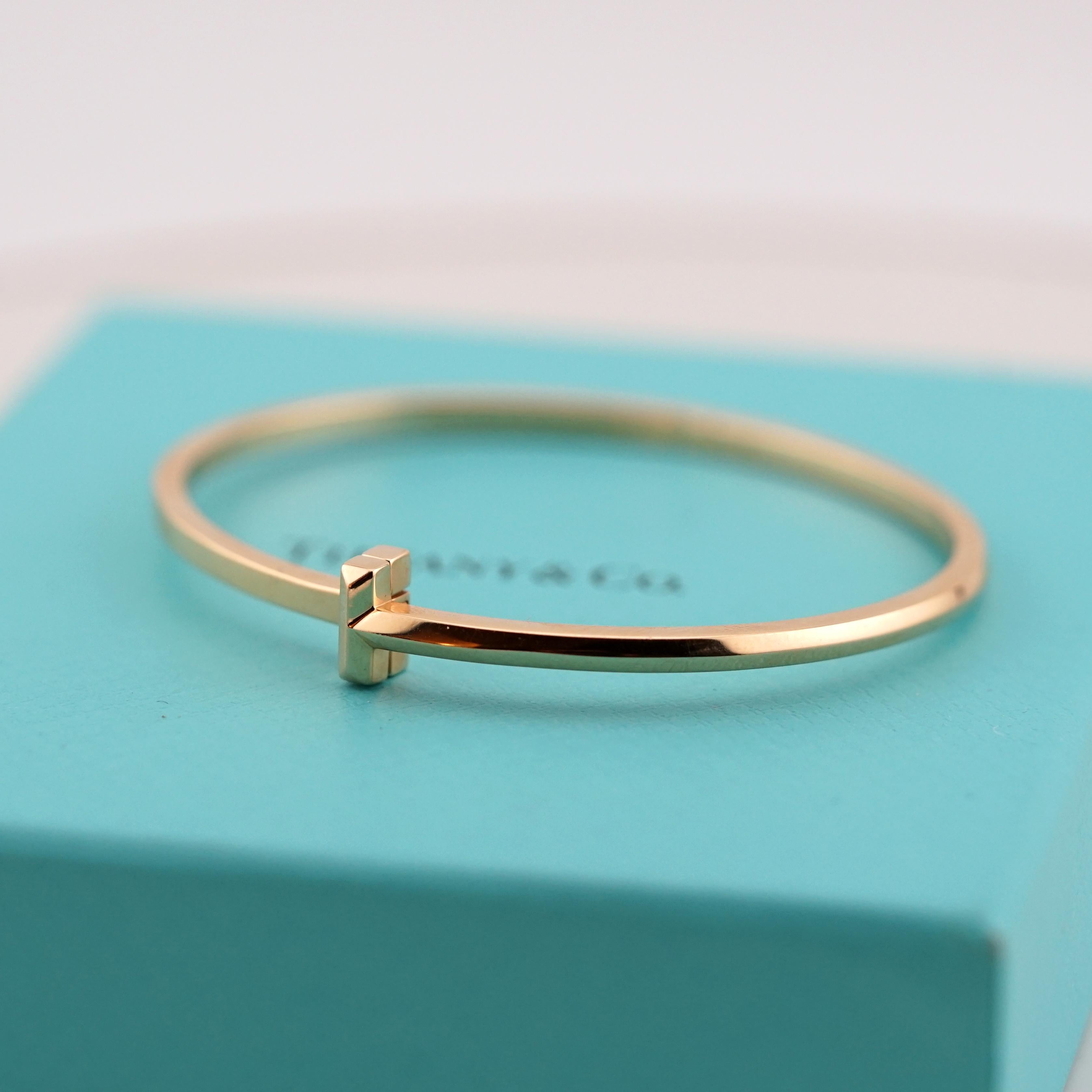 This elegant Tiffany & Co. bangle from the iconic T Collection is crafted in 18K yellow gold. Featuring a minimalist and modern design with the signature 