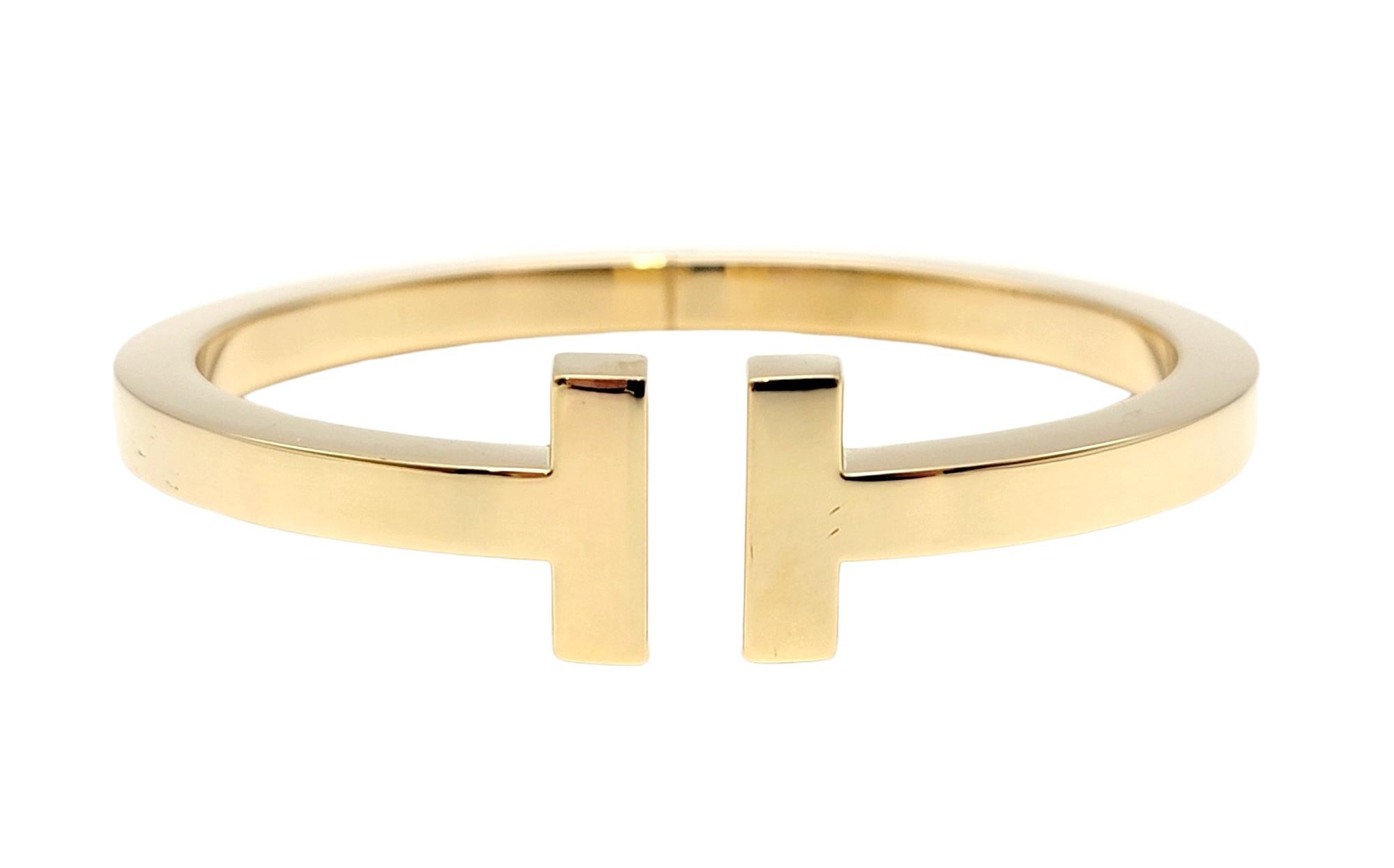 See modern sophistication at its finest with this sleek and stunning Tiffany T bracelet. Luxurious polished 18 karat yellow gold fills the piece, highlighting the clean lines and contemporary design. Pair it with other bracelets for a trendy,