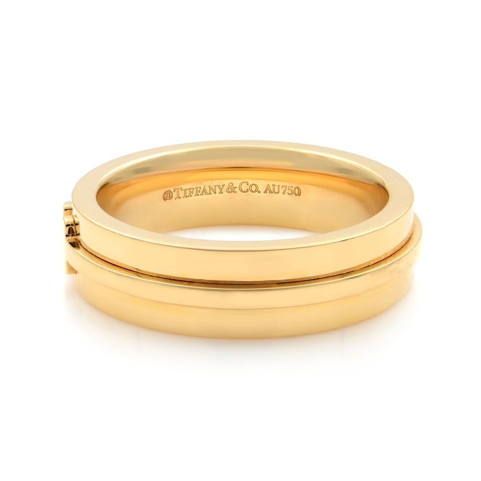 Tiffany & Co T collection wide unisex ring. Graphic angles and clean lines blend to create the beautiful clarity of the Tiffany T collection. Hallmark: Tiffany & Co. Au 750. Crafted in 18K yellow gold. Width: 5.5mm. 2.5mm thickness. Ring size 9.