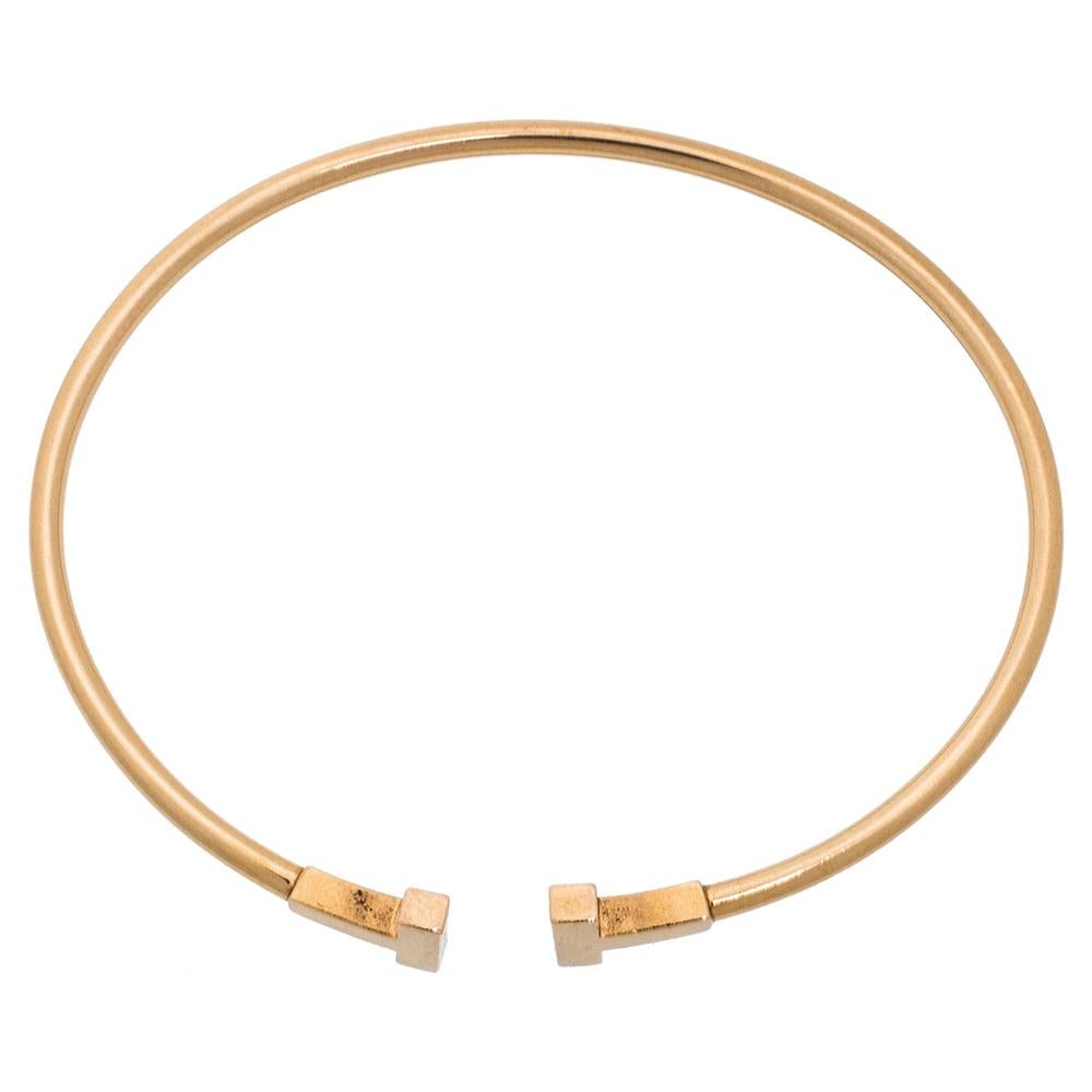 Awe-inspiring and radiating sophistication, this T Wire bracelet from Tiffany & Co. is a piece that you will always cherish wearing! Crafted from 18K rose gold, it features a wire-like band that carries the letter 'T' at both ends. It has the