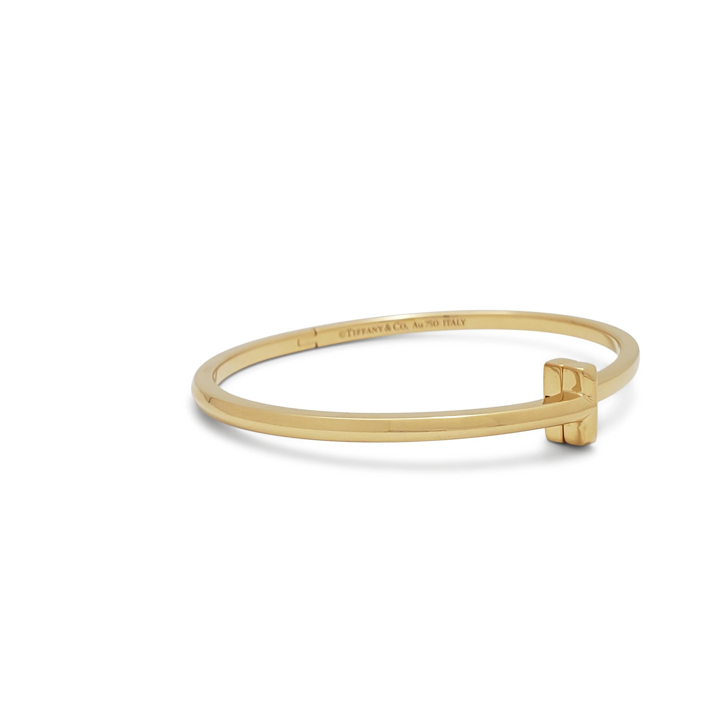 Authentic Tiffany & Co. T1 bangle crafted in 18 karat yellow gold.  The sleek design wraps around the wrist and culminates in a bold 'T' motif that also serves as the clasp.  Size small, will fit up to a 5.75 inch wrist.  Signed Tiffany & Co.,