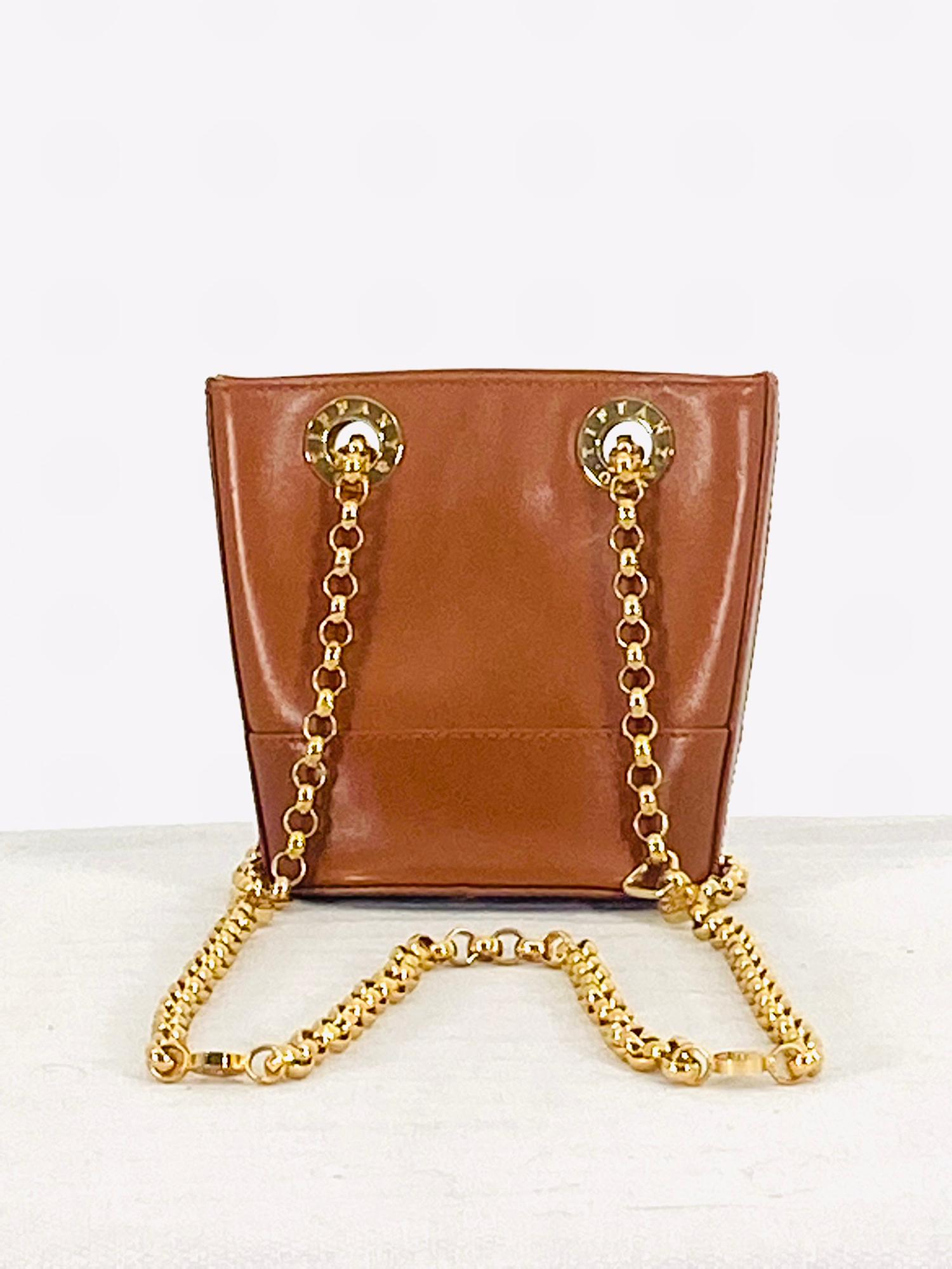 Sac à bandoulière de style seau en cuir havane de Tiffany & Co, doté de matériel doré et d'une bandoulière en chaîne dorée. Le sac ovale à dessus ouvert possède un seul compartiment à fermeture éclair, doublé en daim. En très bon état avec quelques