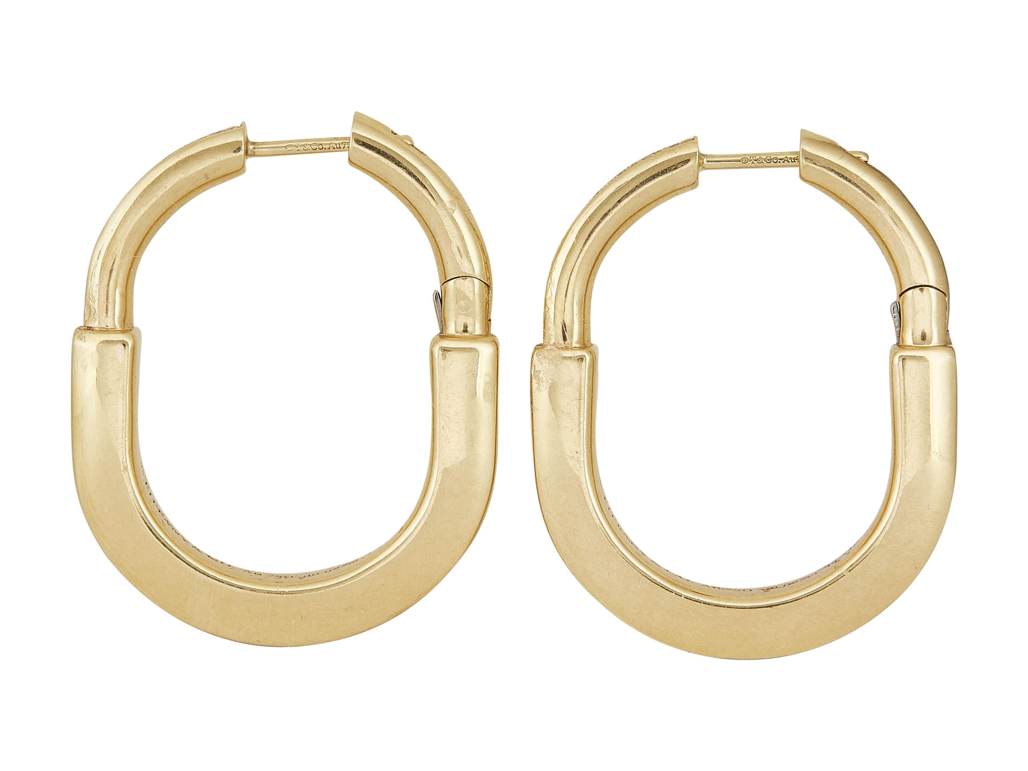 Gli orecchini: Un paio di Tiffany & Co. Orecchini a cerchio Tiffany Lock. Questo modello Medium è realizzato in oro giallo a diciotto carati con diamanti rotondi taglio brillante. 

Le condizioni sono ottime. Leggera usura superficiale, compresi