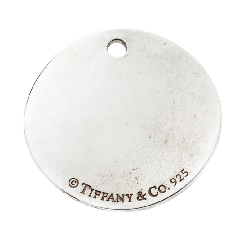 Tiffany & Co.’s Notes pendant charm is an iconic piece to own. The sterling silver pendant is shaped in a circle and engraved with Tiffany’s store location details as a note- ‘Fifth Avenue New York’. Style up your plain chains with this