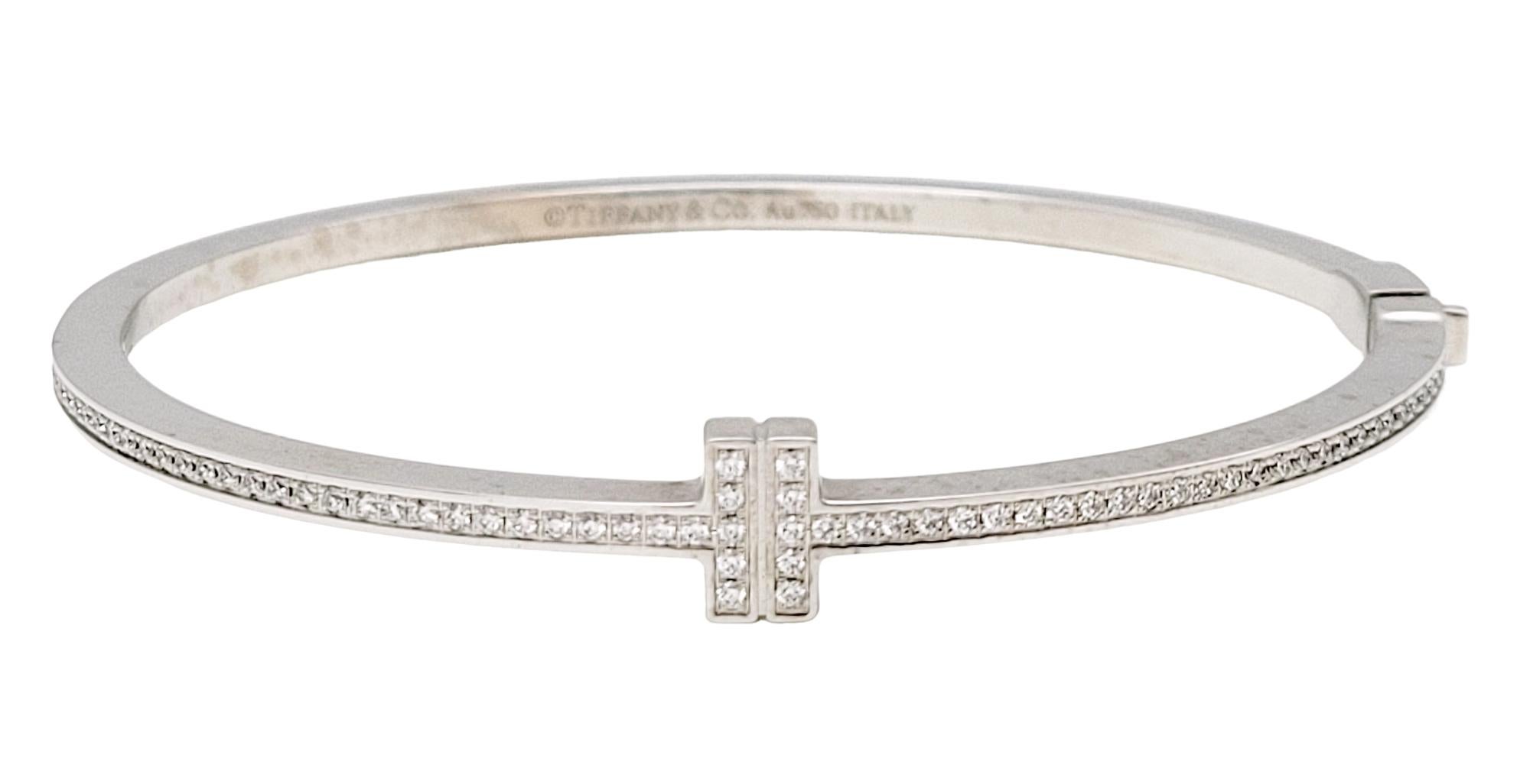 Introducing the exquisite Tiffany T Diamond Hinged Wire Bangle in 18k White Gold, a timeless piece that encapsulates elegance and sophistication. This sleek bangle design features a striking center motif adorned with dazzling diamonds, adding a