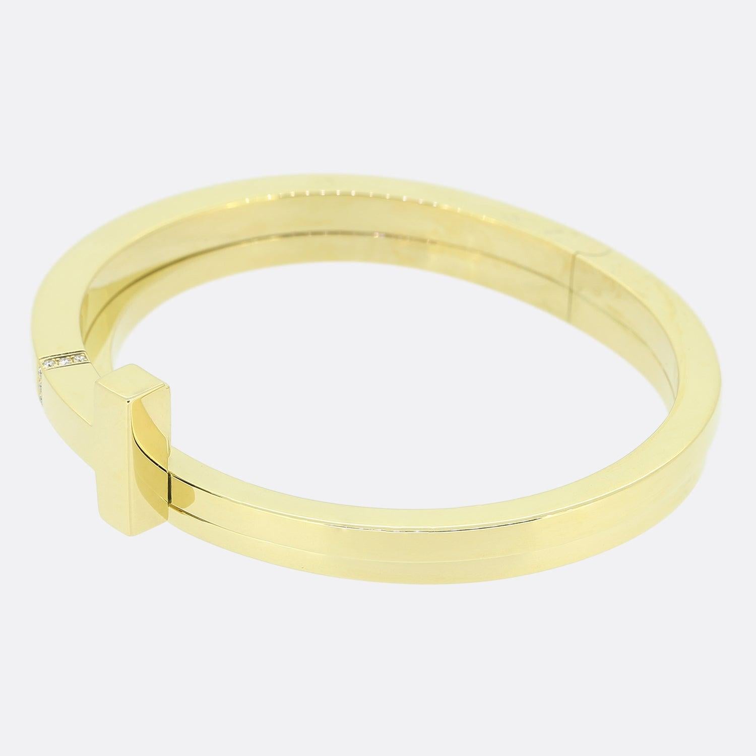 Here we have a wonderful bangle from the world renowned jewellery designer, Tiffany & Co. From the Tiffany T collection, this sleek 18ct yellow gold bracelet features the signature T design enhanced with brilliant diamonds with a 0.05 total carat