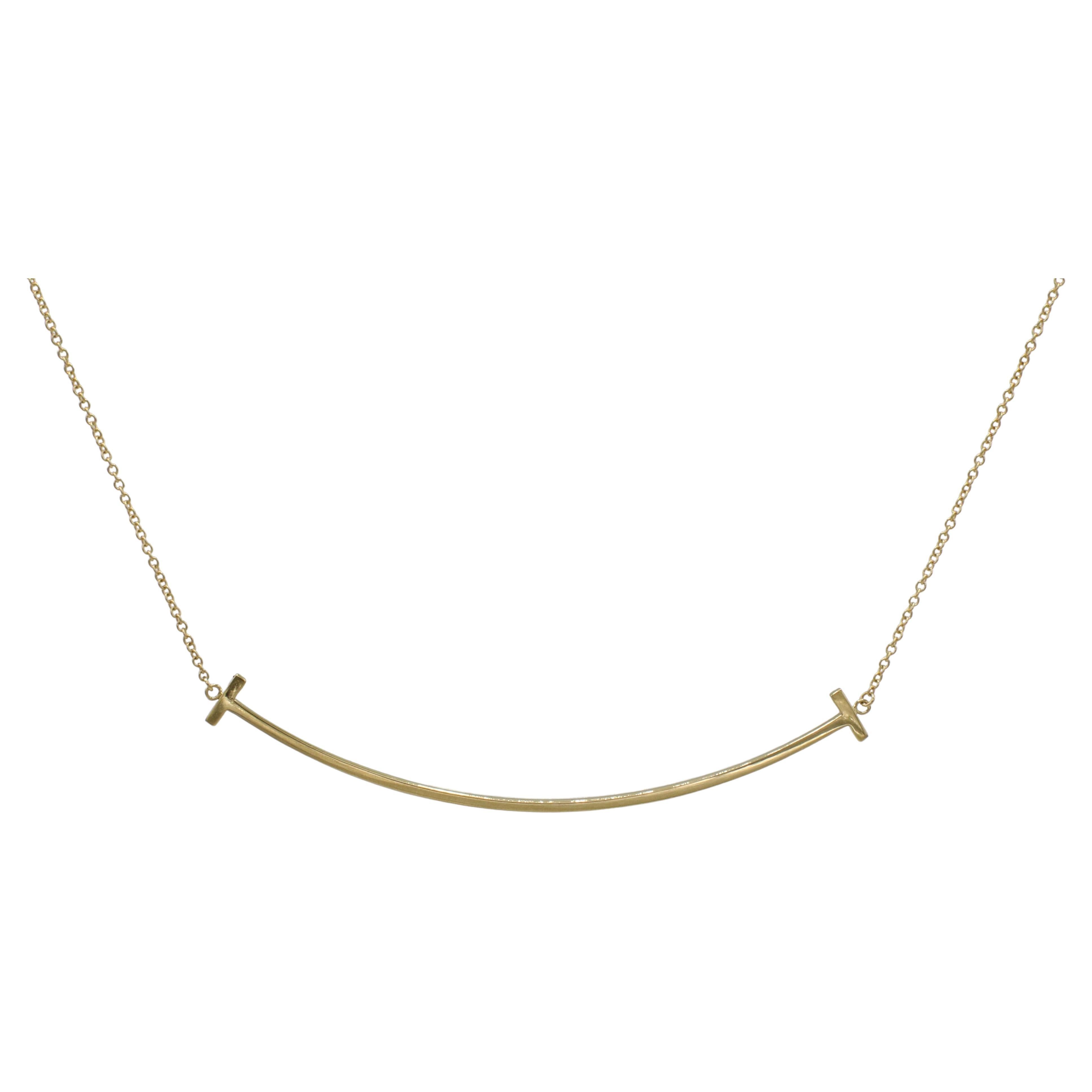 Tiffany & Co. Collier à pendentif sourire en or jaune 18 carats de Tiffany T. Large 
Métal : or jaune 18k
Poids : 3.72 grammes
Pendentif : 2.75 pouces
Longueur : chaîne réglable de 16 à 18 pouces
Prix de détail : 1 625 USD
Signé : ©Tiffany & Co.