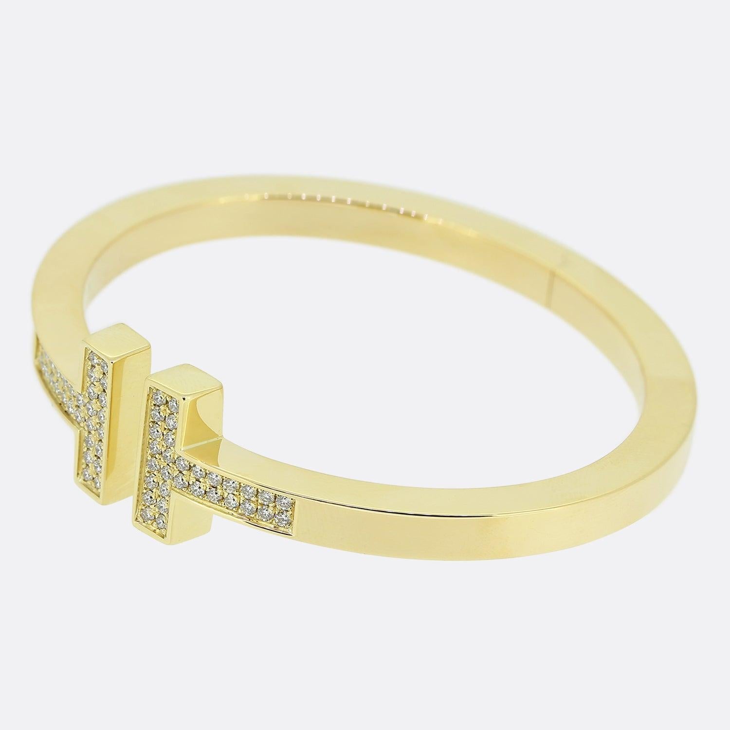 Here we have a modern, sophisticated bangle from the world renowned jewellery designer, Tiffany & Co. An 18ct yellow gold bracelet has been crafted into Tiffany's iconic double T design and pavé set with 60 round brilliant cut diamonds. 

Condition: