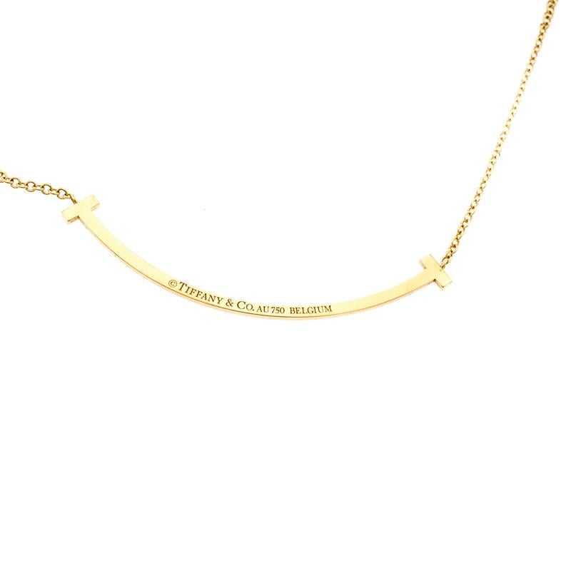 Modern and amazing, the beautiful pendant necklace features Tiffany & Co.'s signature Tiffany T letter symbol that resembles strength and resilience. Crafted from 18k yellow gold metal, the pendant is shaped like a smile with letter T on the