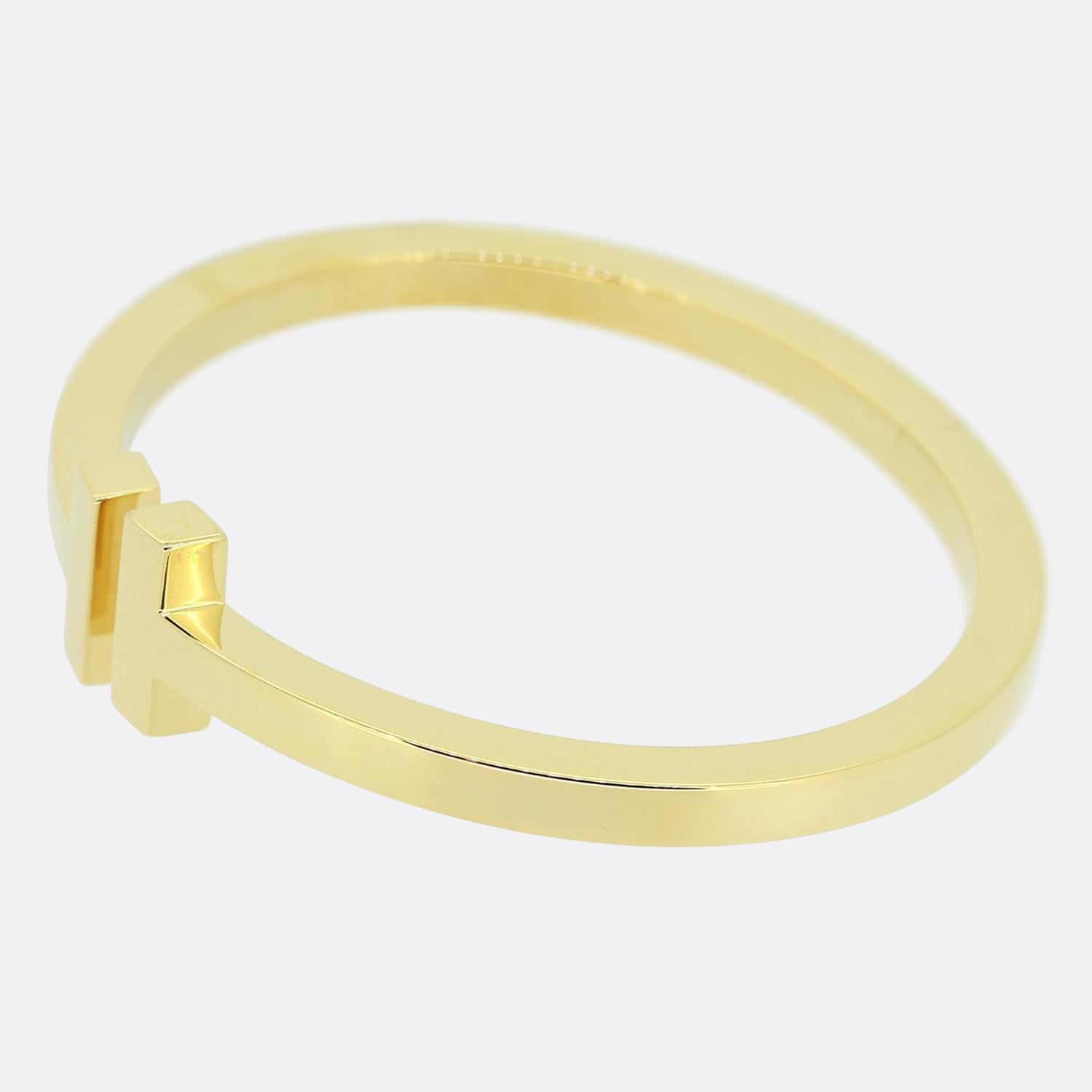 Nous avons ici un magnifique bracelet du créateur de bijoux de renommée mondiale, Tiffany & Co. Issu de la collection Tiffany T, cet élégant bracelet en or jaune 18 ct présente le motif en T emblématique, rehaussé d'une finition polie unie et d'un