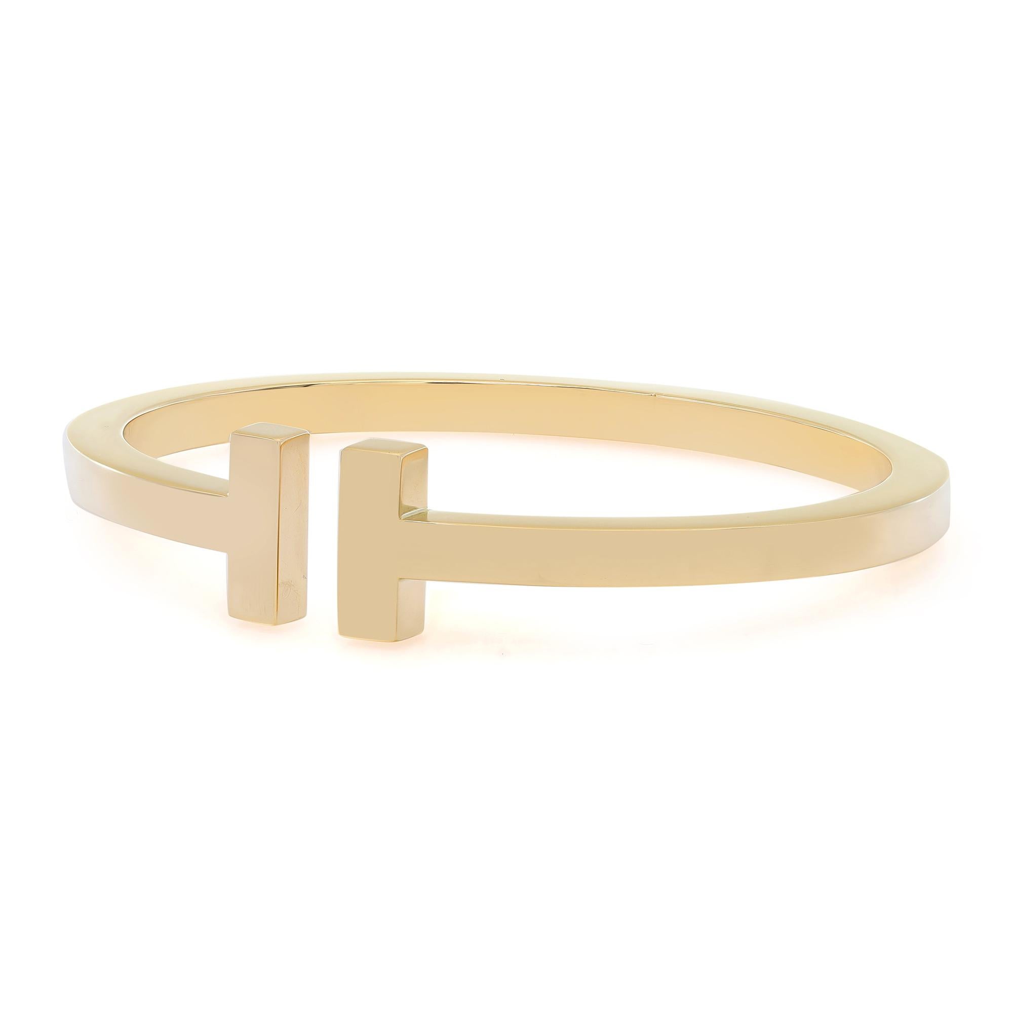 This bold Tiffany & Co. bracelet exudes sophistication. The Tiffany T collection comes in a sleek bangle design, crafted in highly polished 18K yellow gold. Stackable bracelet for a modern look. Size: large. Fits wrists up to 6.75 inches. Total