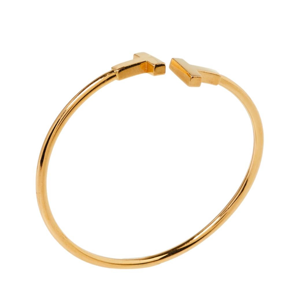Awe-inspiring and radiating sophistication, this T Wire bracelet from Tiffany & Co. is a piece that you will always cherish wearing! Crafted from 18K yellow gold, it features a wire-like band that carries the letter 'T' at both ends. It has the
