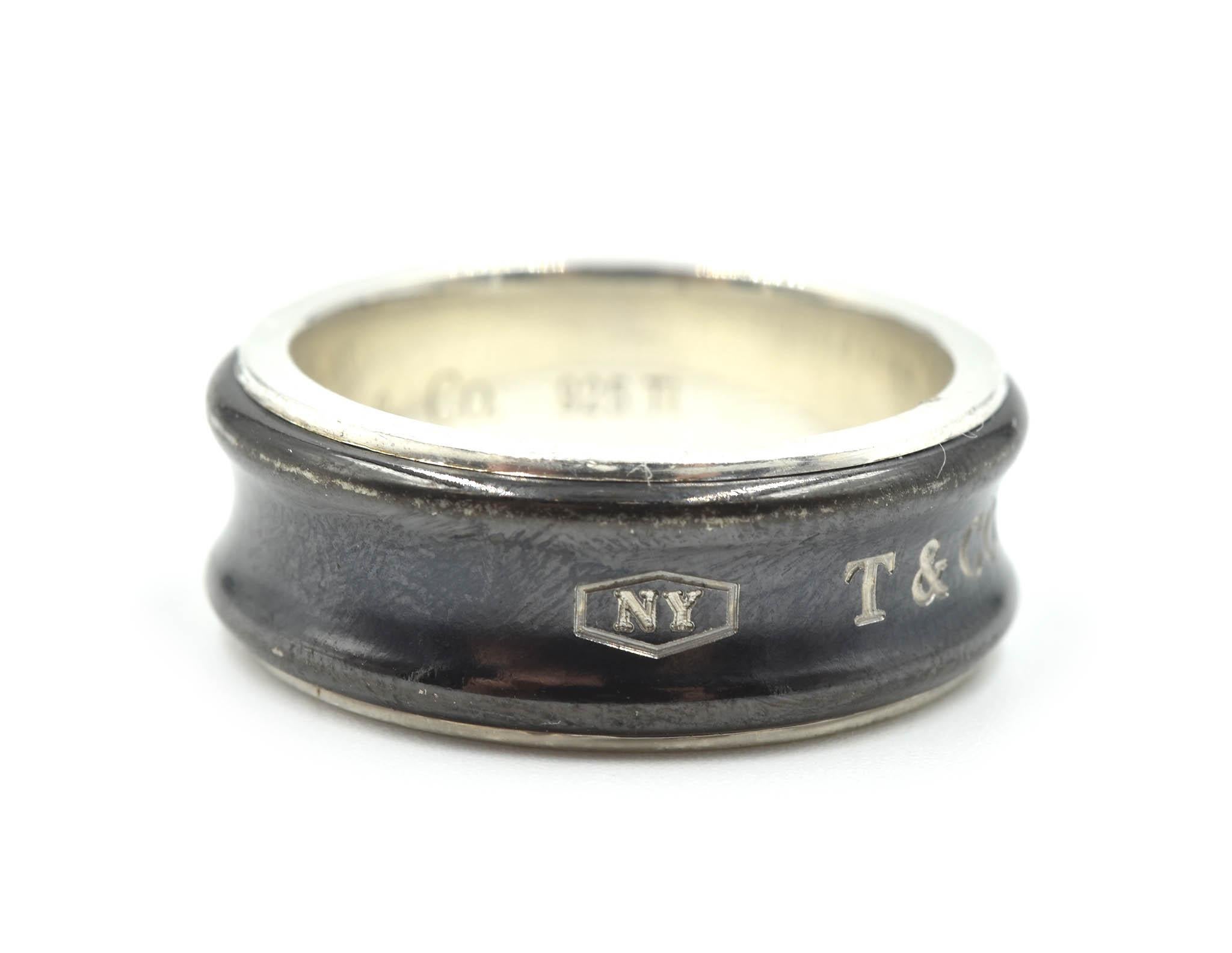 This is a timeless design by a classic designer! Tiffany & Co made this gents wedding band in titanium with sterling silver! The band is size 8; and measures 8.48mm in length and 2.32mm in width. The wedding band weighs 8.00 grams. Hallmarked on the