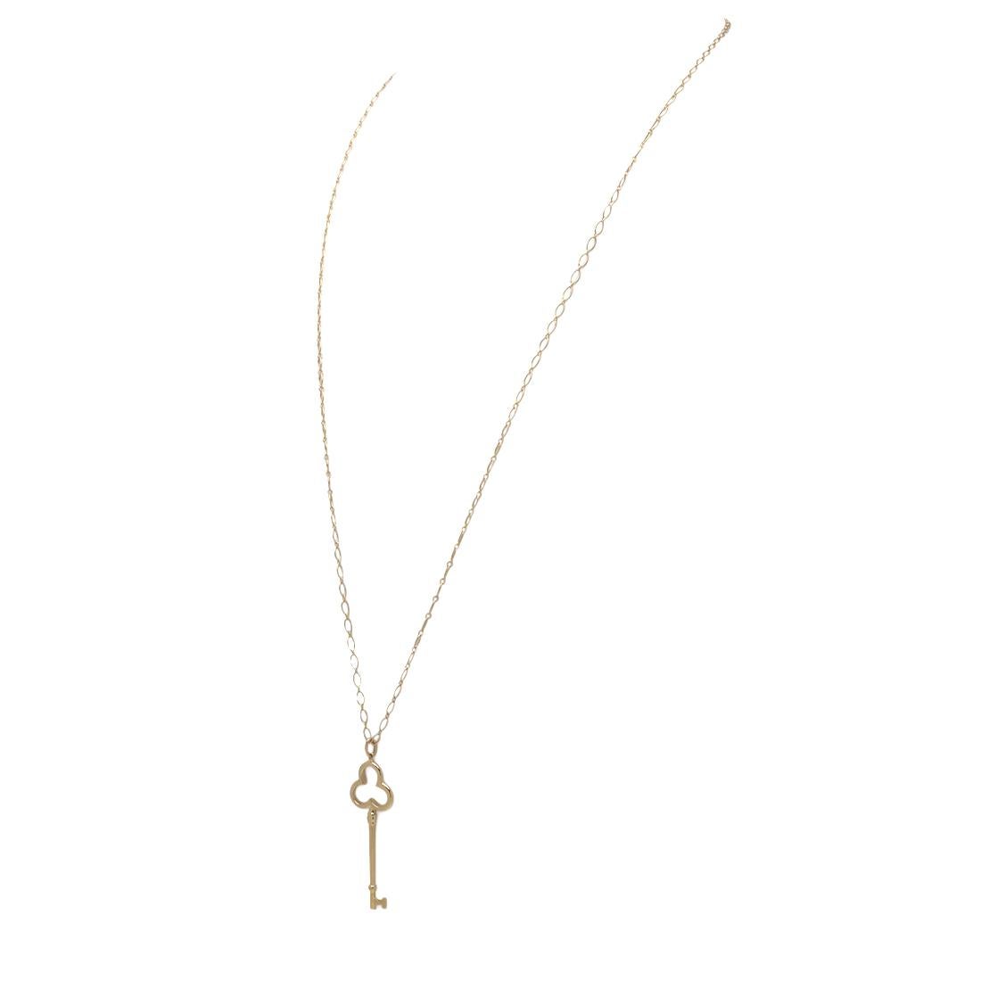 Authentic Tiffany & Co. 'Trefoil Key' pendant crafted in 18 karat yellow gold. The pendant hangs from a Tiffany & Co. oval-link chain necklace crafted in 18 karat yellow gold and measuring 30 inches in length. The pendant measures 59mm in length and