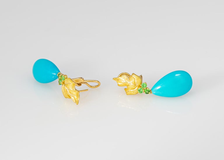 A fantastic example of Tiffany quality and design. Beautiful 18k gold leaf motif designs are paired with exceptional turquoise drops and accented with brilliant cut tsavorite garnets. A chic statement piece. 1 3/4 inches in length.