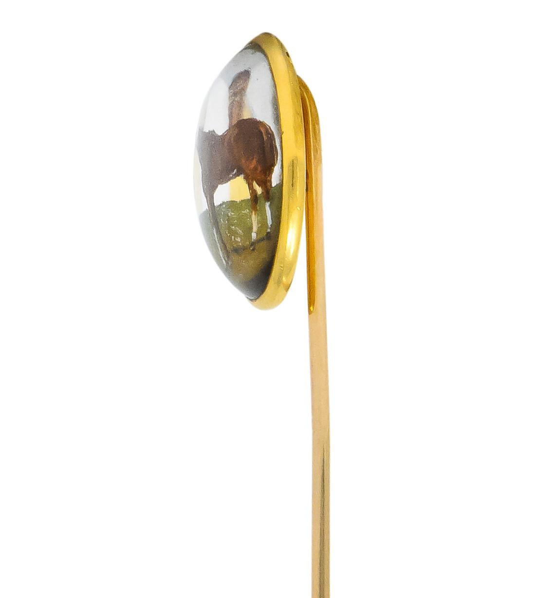 Centering a transparent rock crystal measuring approximately 18.5 mm, bezel set, in a high polished gold surround

Reverse painted depiction of a horse, hand-painted chestnut brown and standing in a lush yellow to green pasture

Fully signed Tiffany