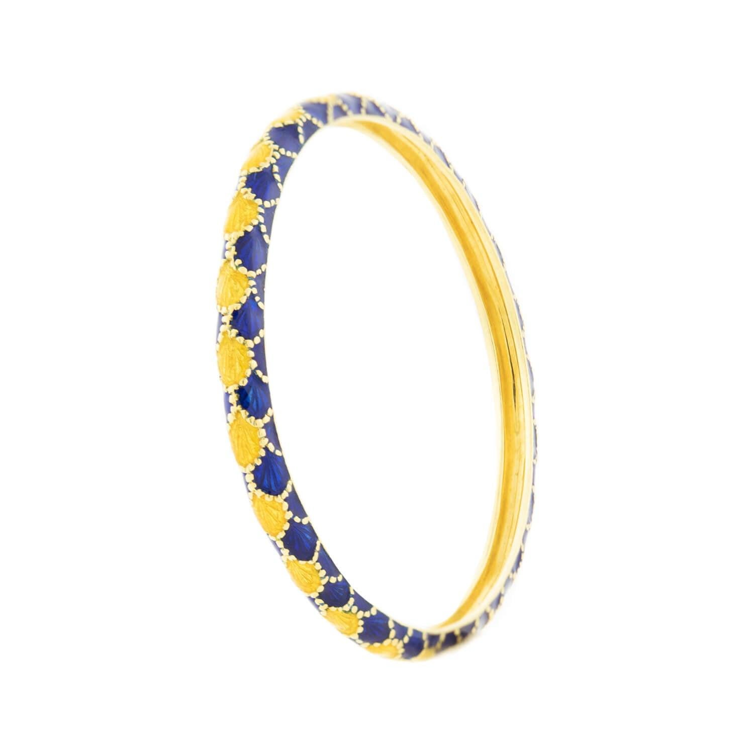 This stylish estate bangle is a signed piece by Tiffany & Co. made in the 1980s! The slip-on bracelet is made of 18k yellow gold with blue and yellow enamel. This bangle features a scale motif with a stipe of yellow scales flanked by overlapping